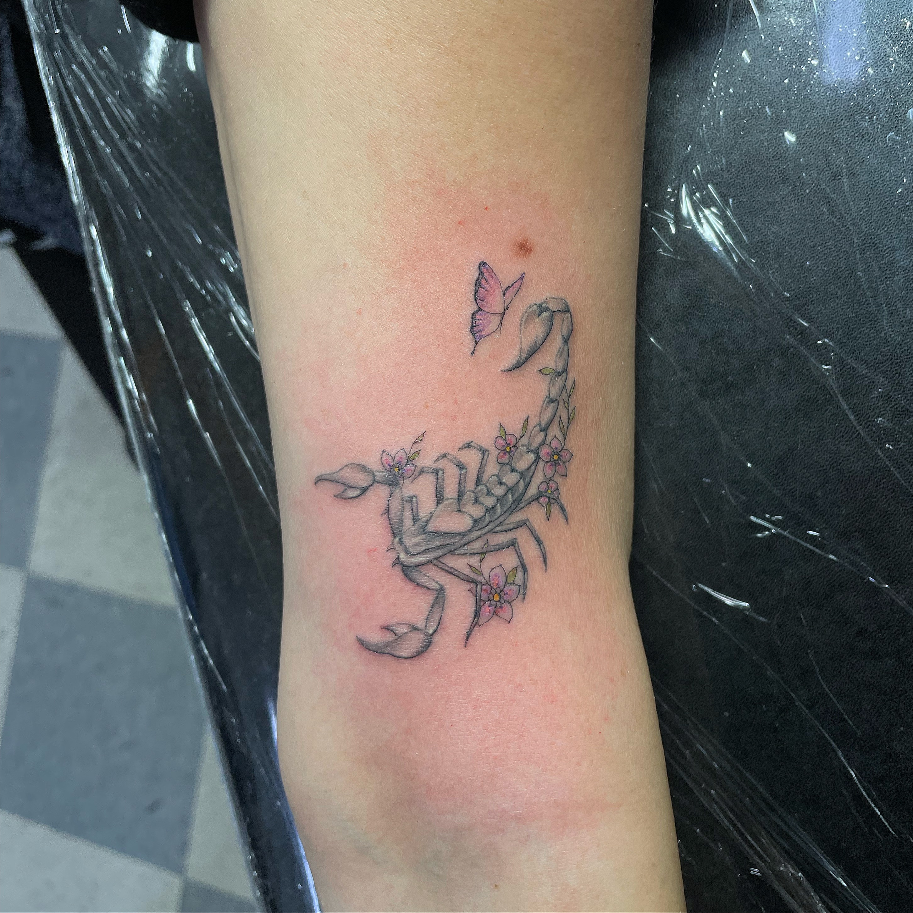 Scorpion with flowers new school tattoo on the forearm by Manny
