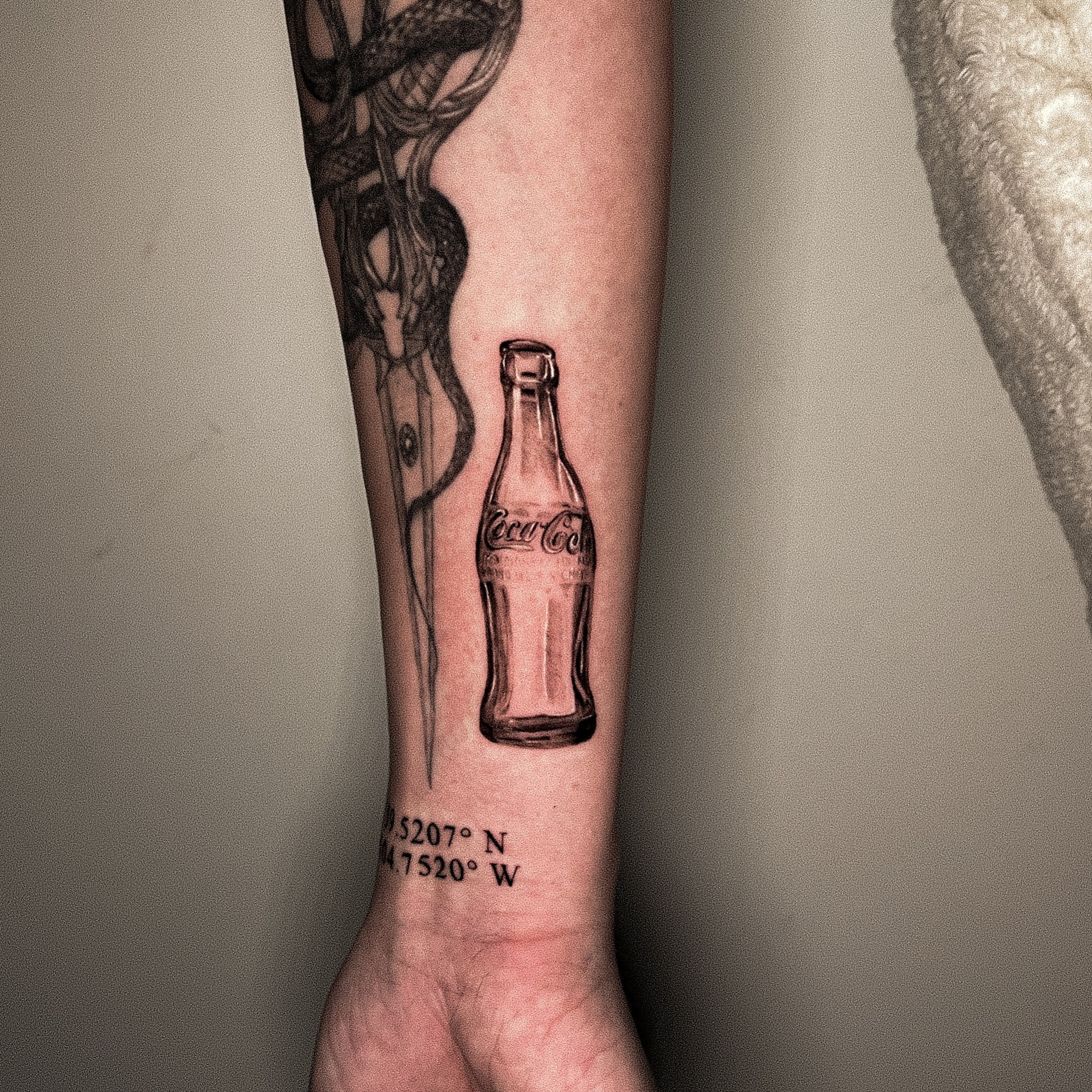 Coca-Cola bottle black and grey tattoo on the forearm by Riley K Turner
