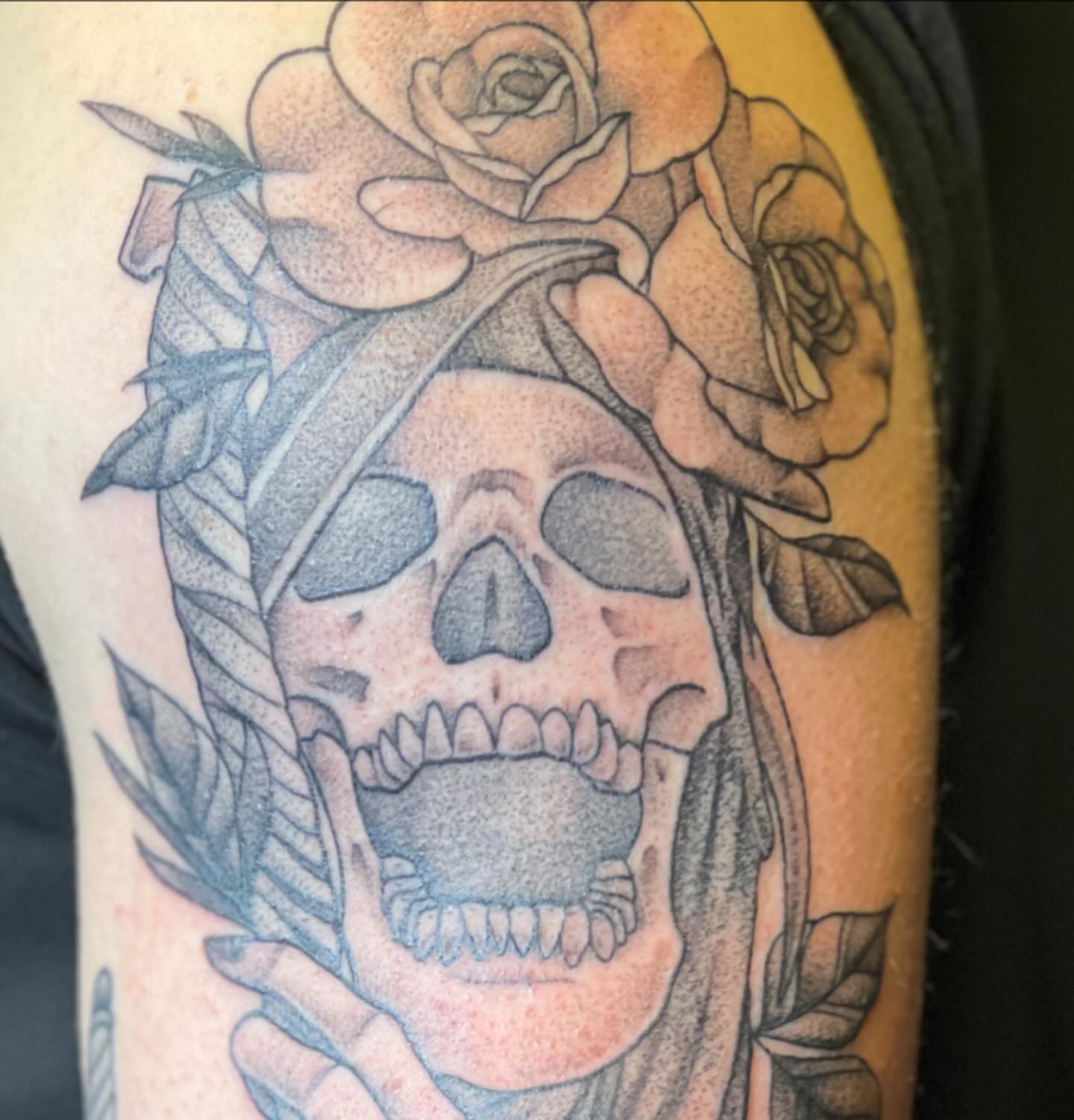Skull with roses dotwork tattoo on the upper arm by Dani McBay