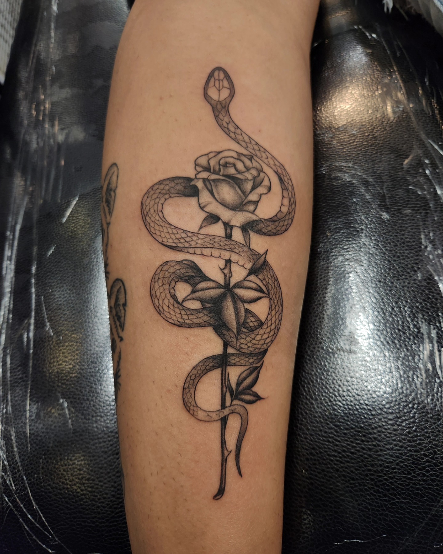 Snake and rose black and grey tattoo on the forearm by Adrian Chavez