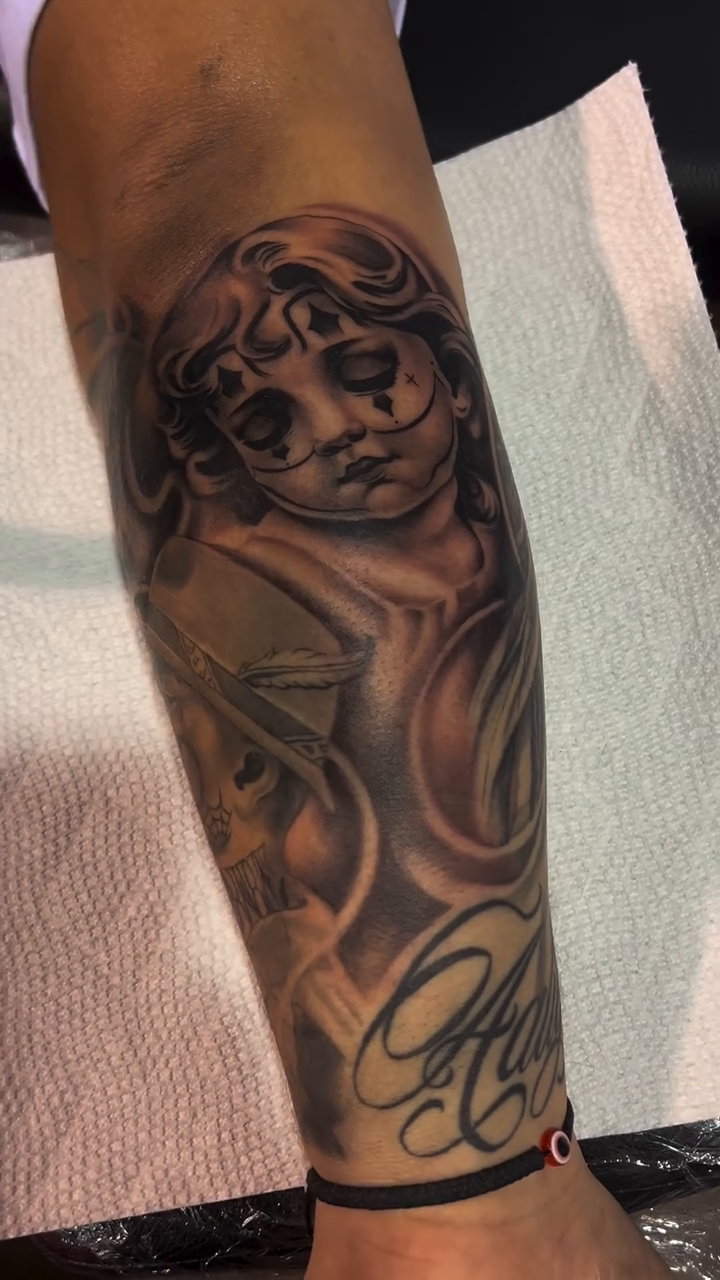 Cherub with clown makeup and script Chicano tattoo by Moose