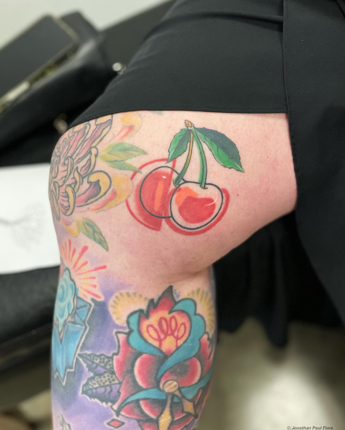 Cherry and floral American traditional tattoo on the thigh by Jonathan Paul Fiore, Austin, Texas