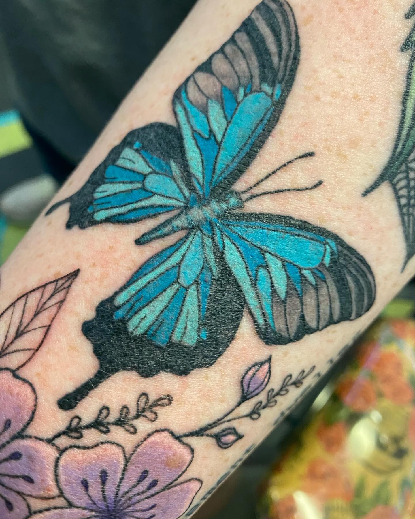 Blue butterfly new school tattoo on the forearm by Tesla Kohl