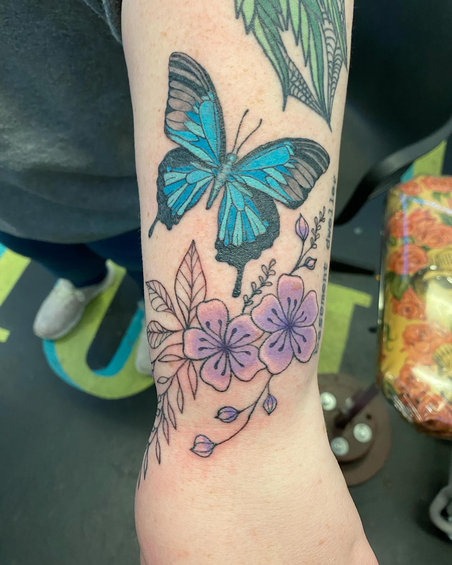 Butterfly and flowers new school tattoo on the forearm by Tesla Kohl