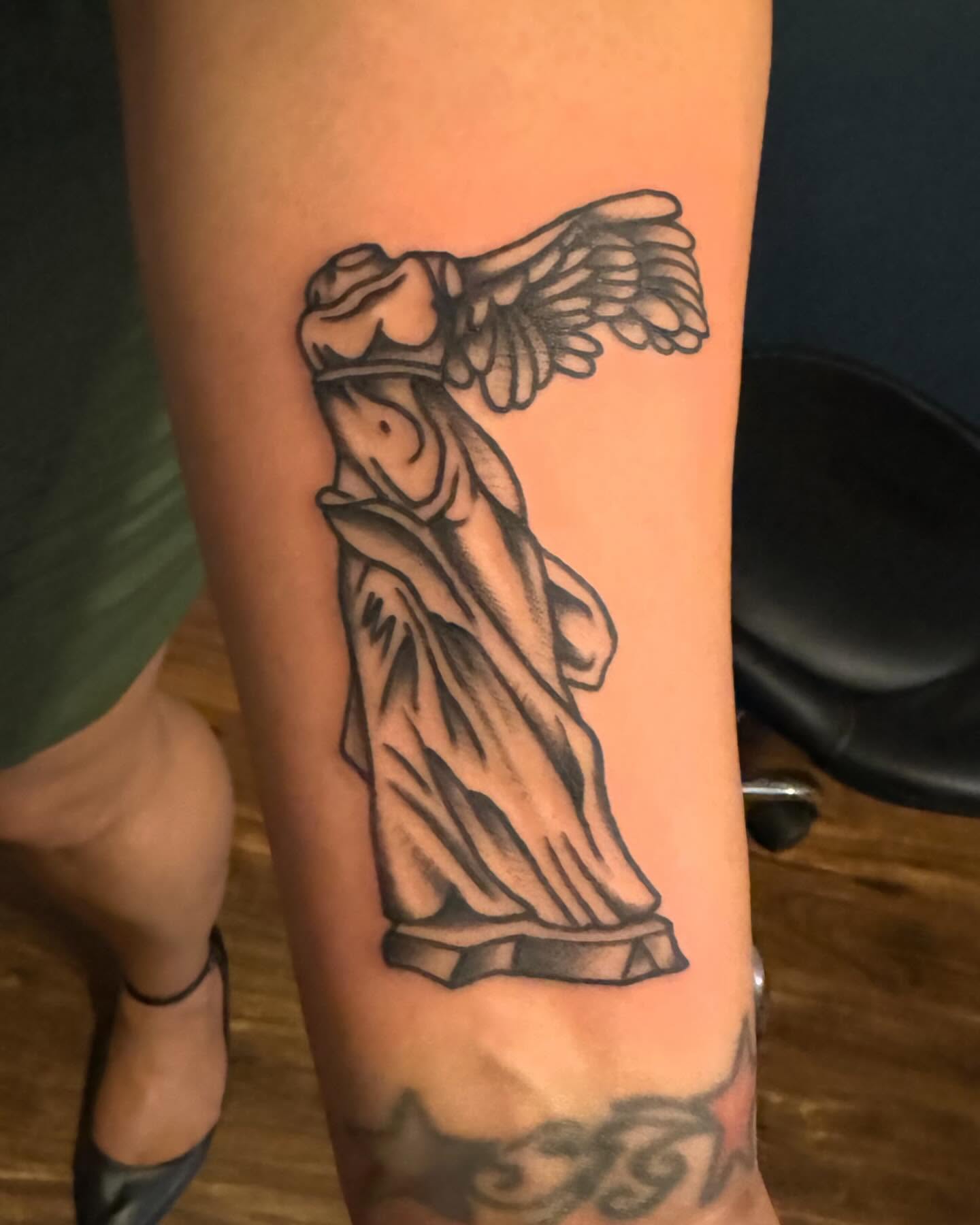 Winged statue black and grey tattoo on the forearm by Dave Shurman