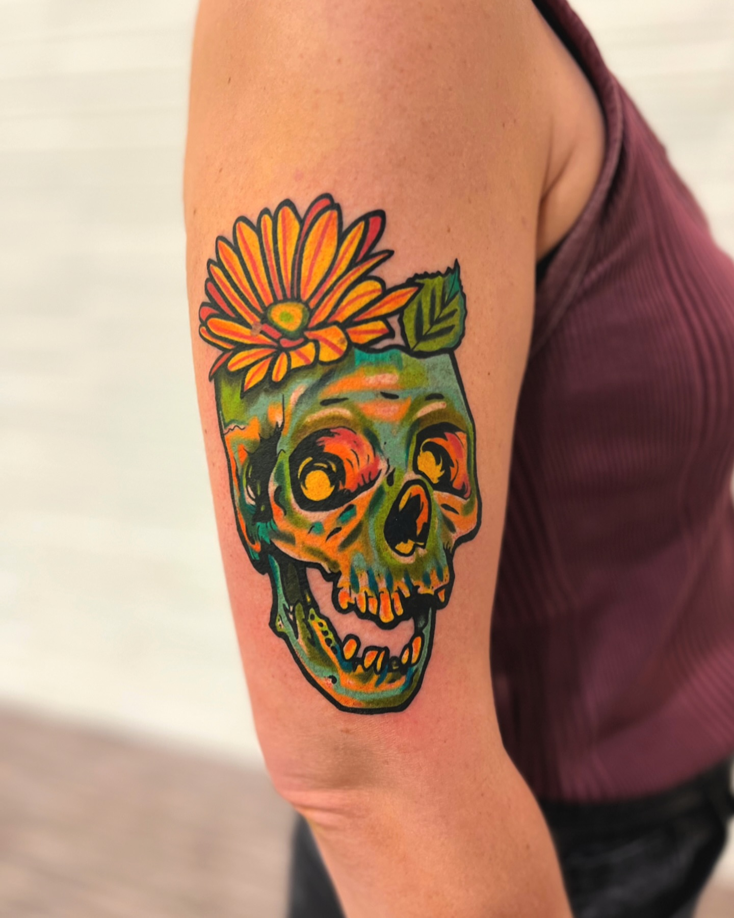 Skull with flower new school tattoo on the upper arm by Hugh Anthony Washington, Hattiesburg, Mississippi
