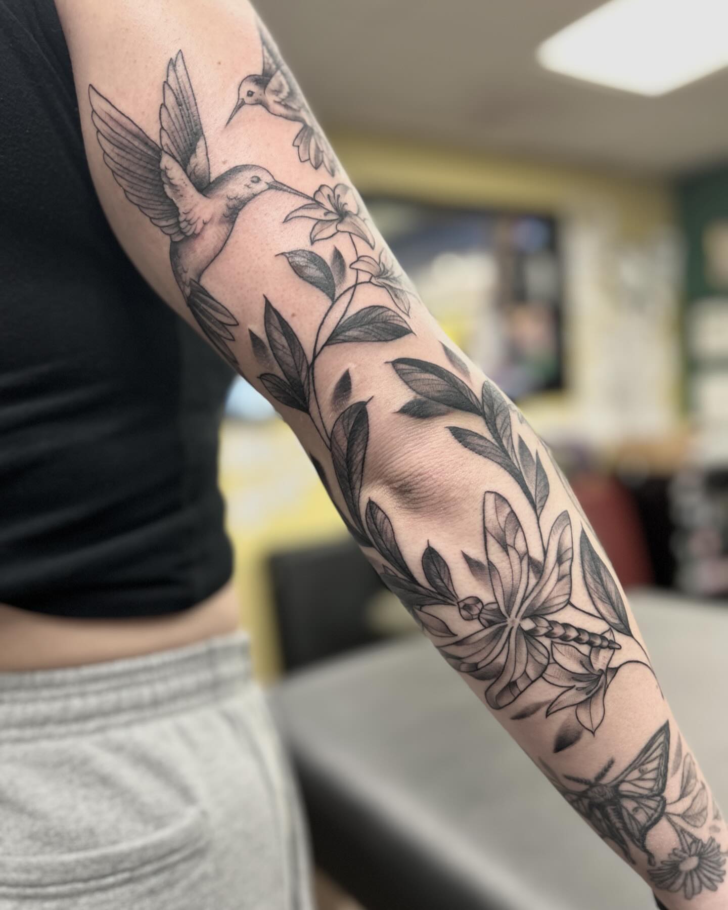 Hummingbird and floral realism tattoo on the forearm by Patricia Cunningham