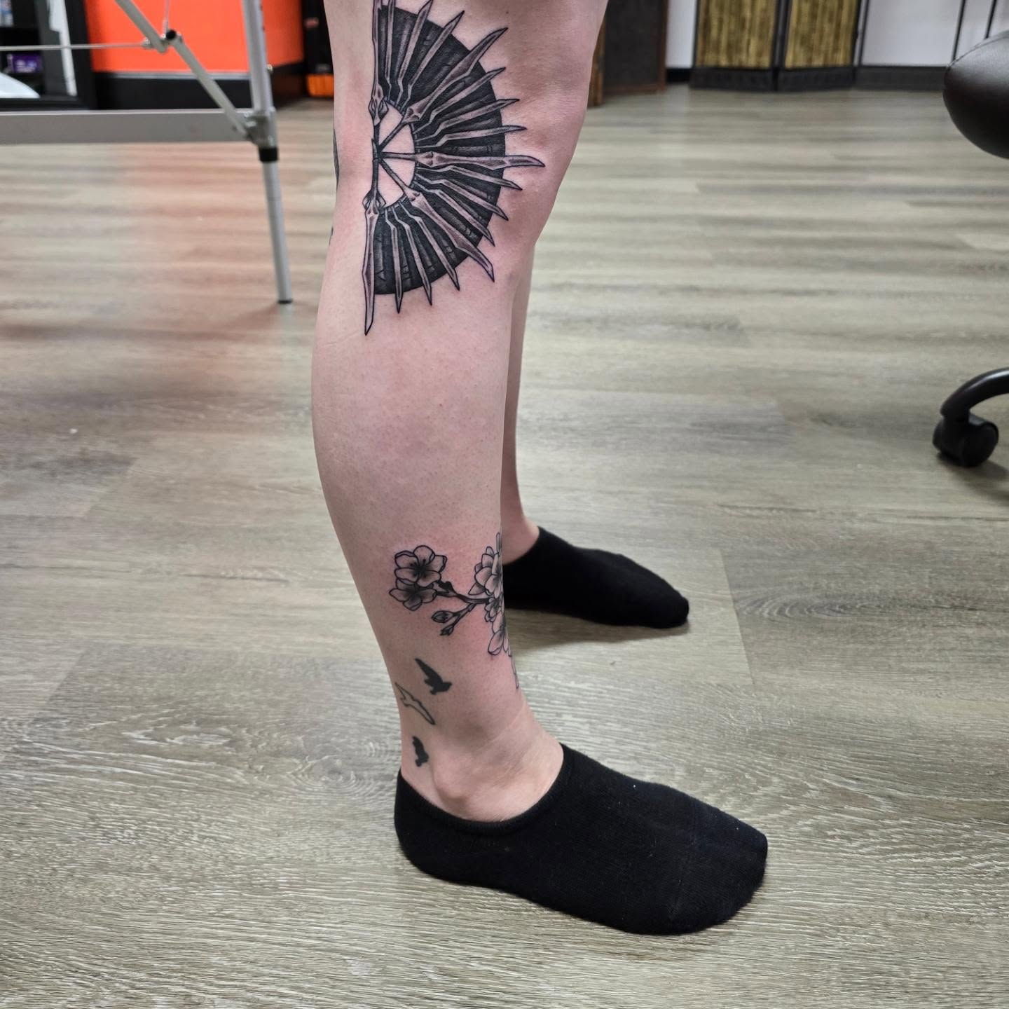 Bird and cherry blossoms black and grey tattoo on the calf by Gene Britton