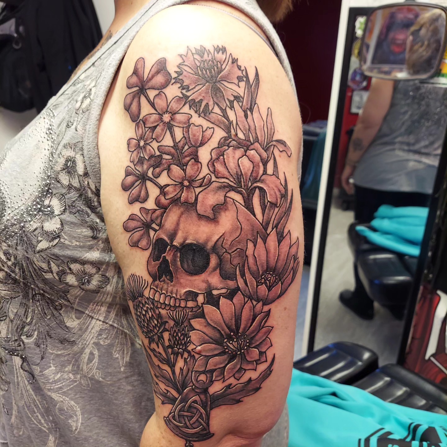 Skull and flowers realism tattoo on the shoulder by Dave Johnson, Billings, Montana