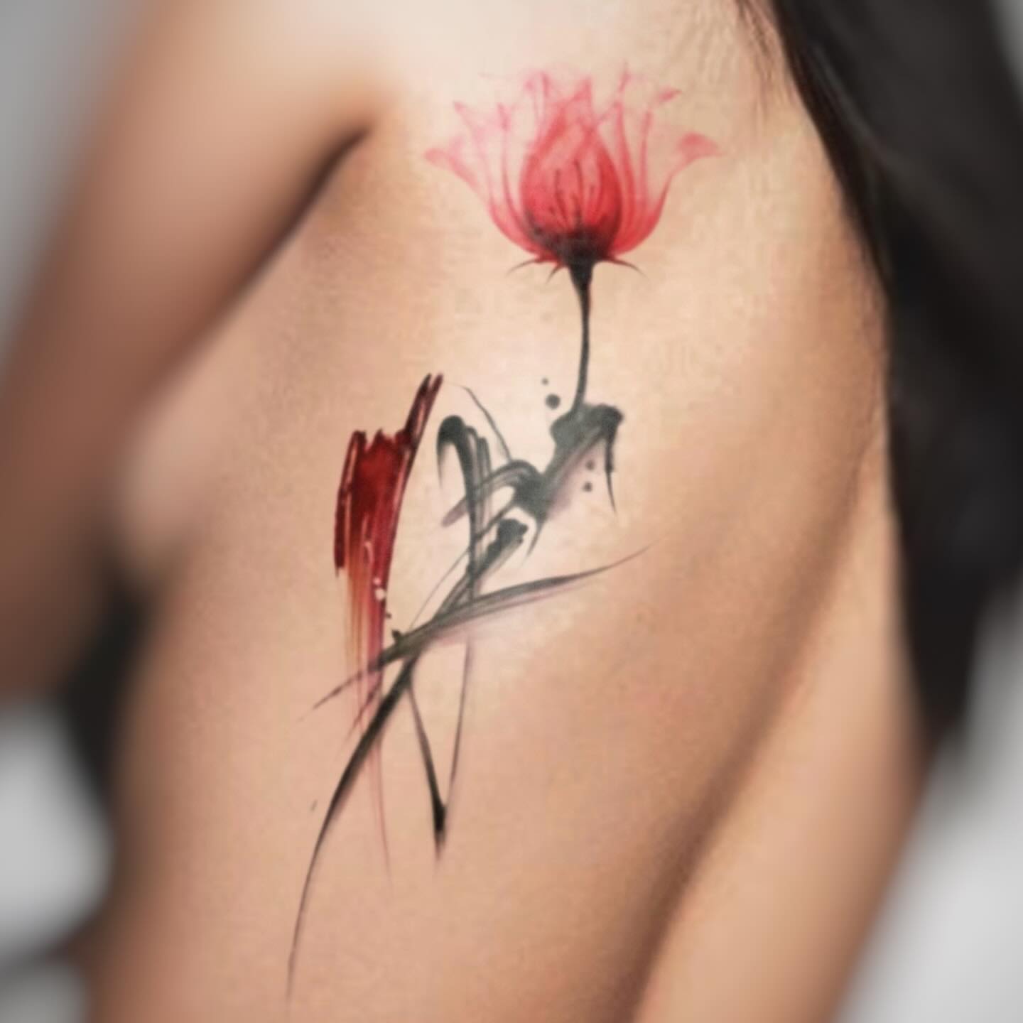 Red flower watercolor tattoo on the shoulder by Banky