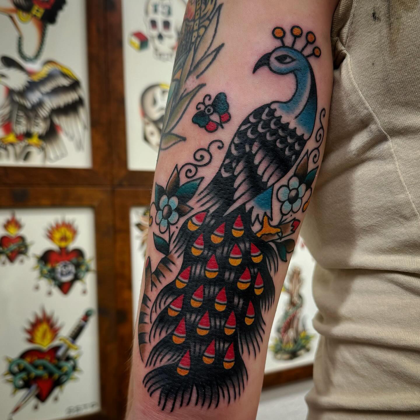 Peacock American traditional tattoo on the forearm by Rogelio Robles