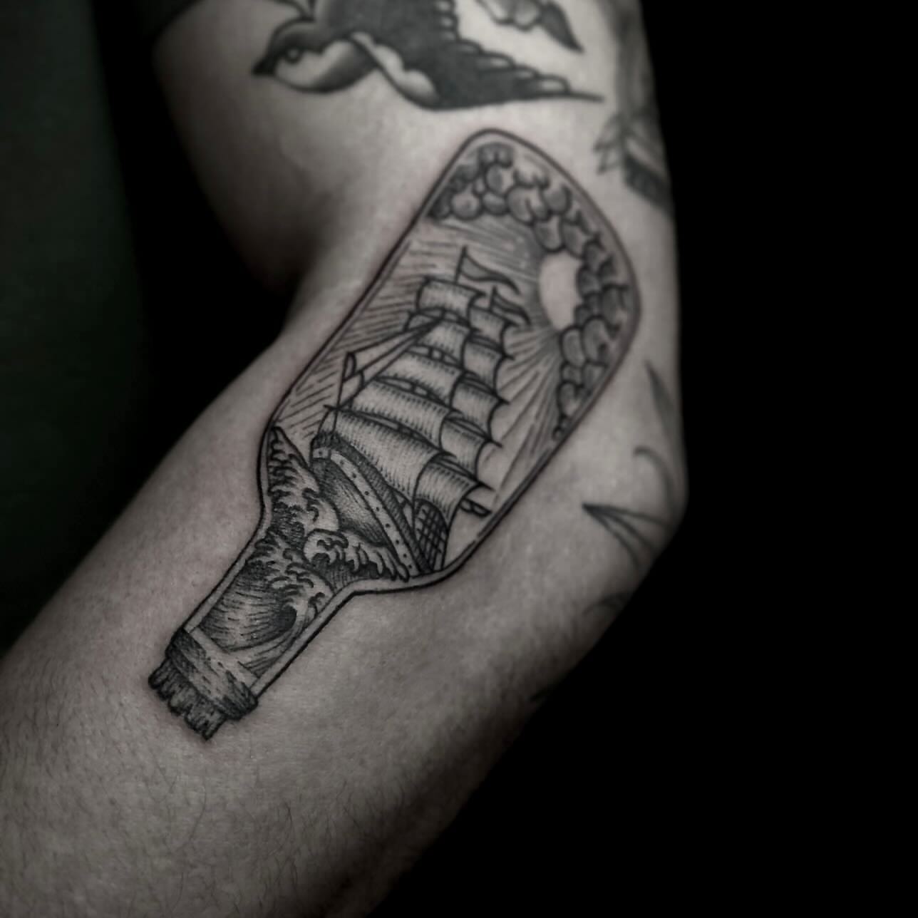 Ship in bottle black and grey tattoo on the forearm by t a y l o r
