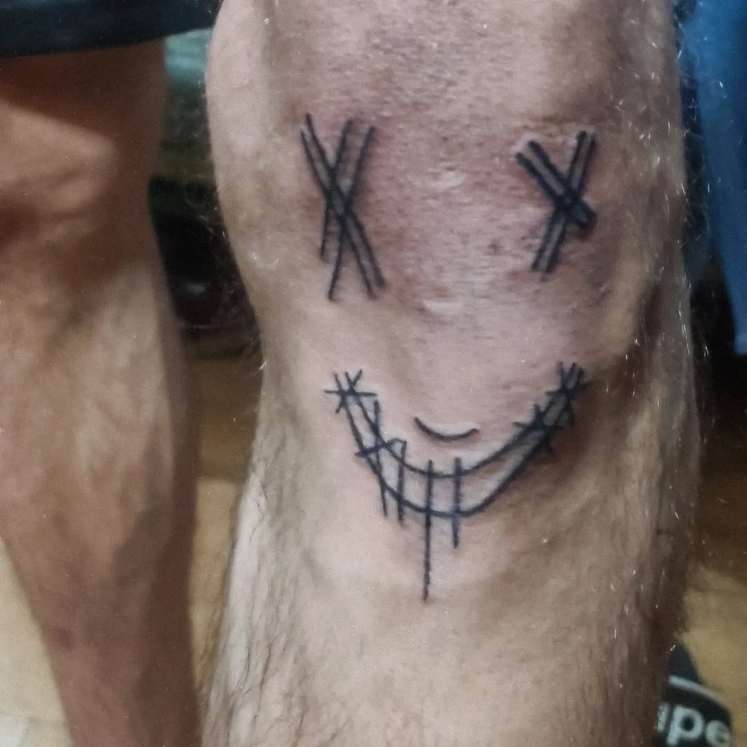 Smiley face with x eyes tattoo on the forearm by Tatuadora & Piercer