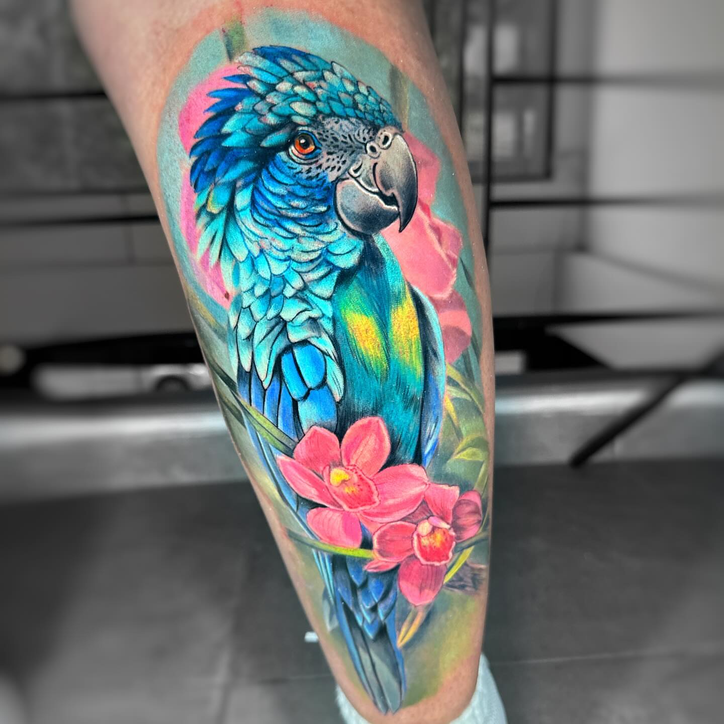 Parrot and flowers realism tattoo on the forearm by Daniela Duque Tattoo