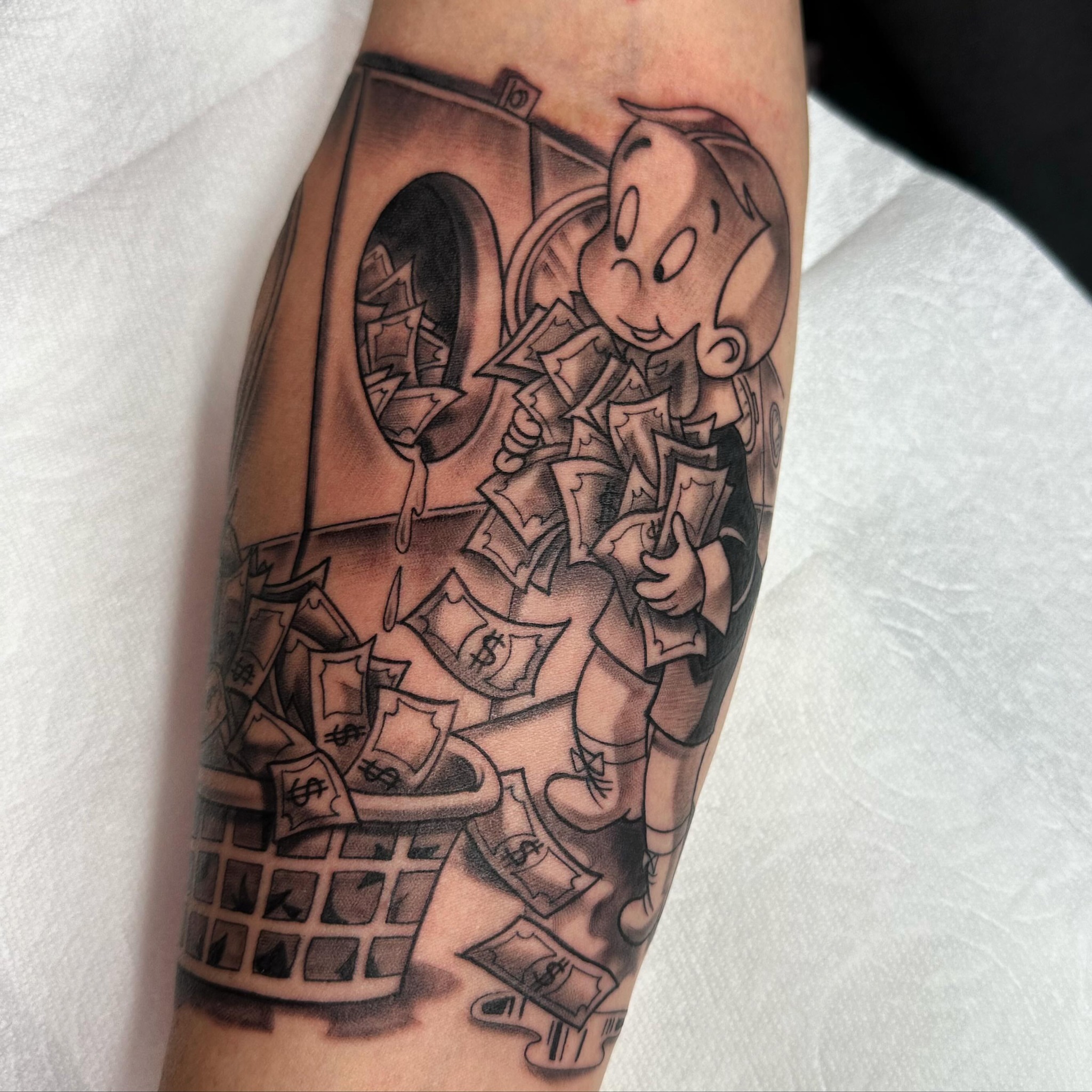 Cartoon character with money black and grey tattoo on the forearm by Yari, Los Angeles, California