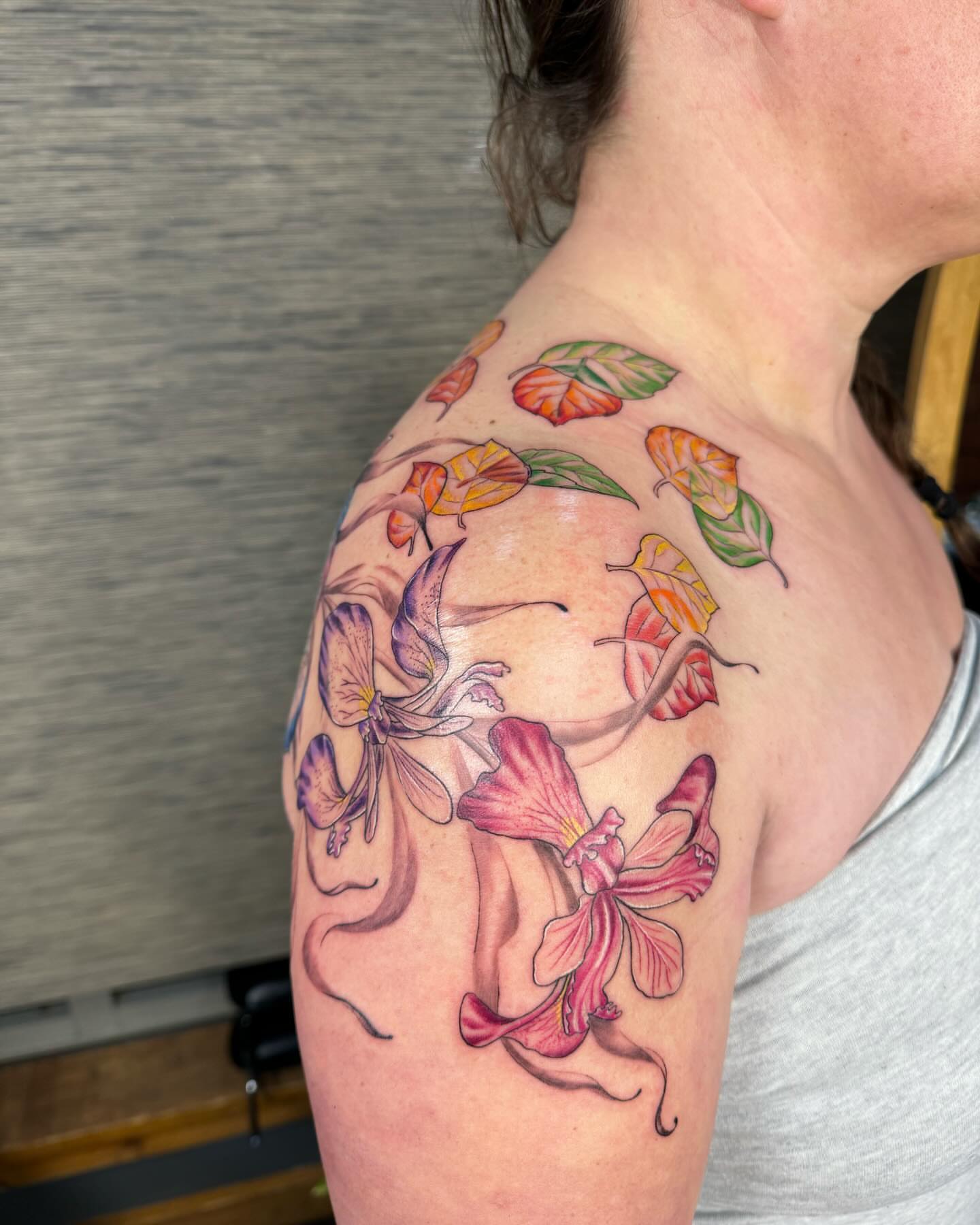 Orchids and leaves new school tattoo on the shoulder by Ian Spencer