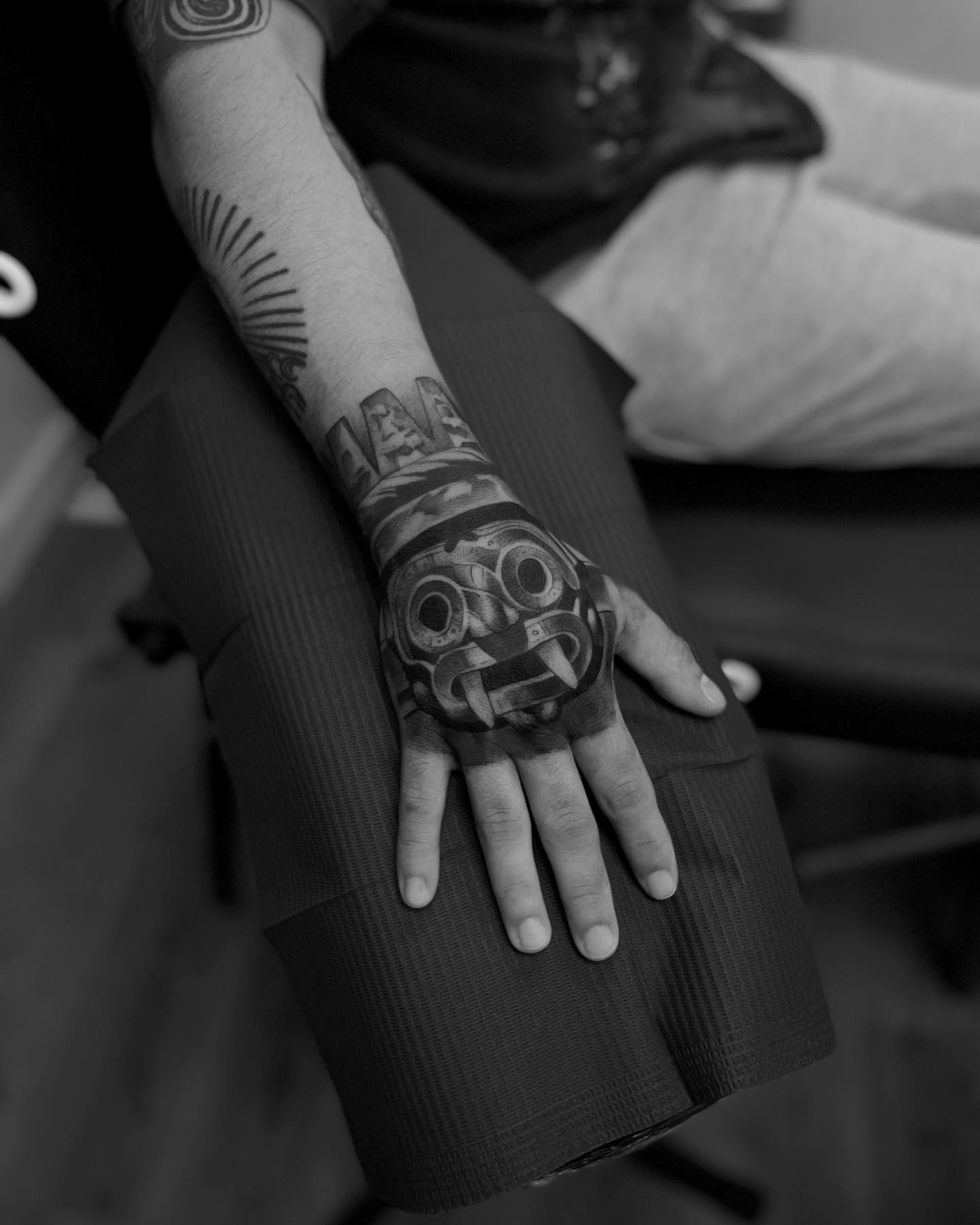 Mask black and grey tattoo on the forearm by Vanessa Valdivia