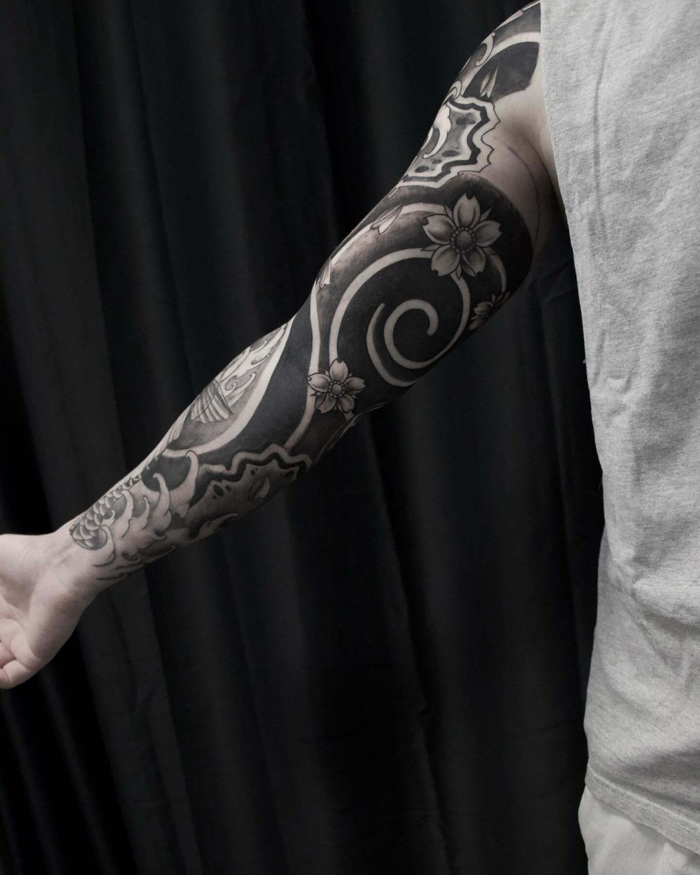 Cherry blossoms and swirls black and grey tattoo on the forearm by Alex Suarez