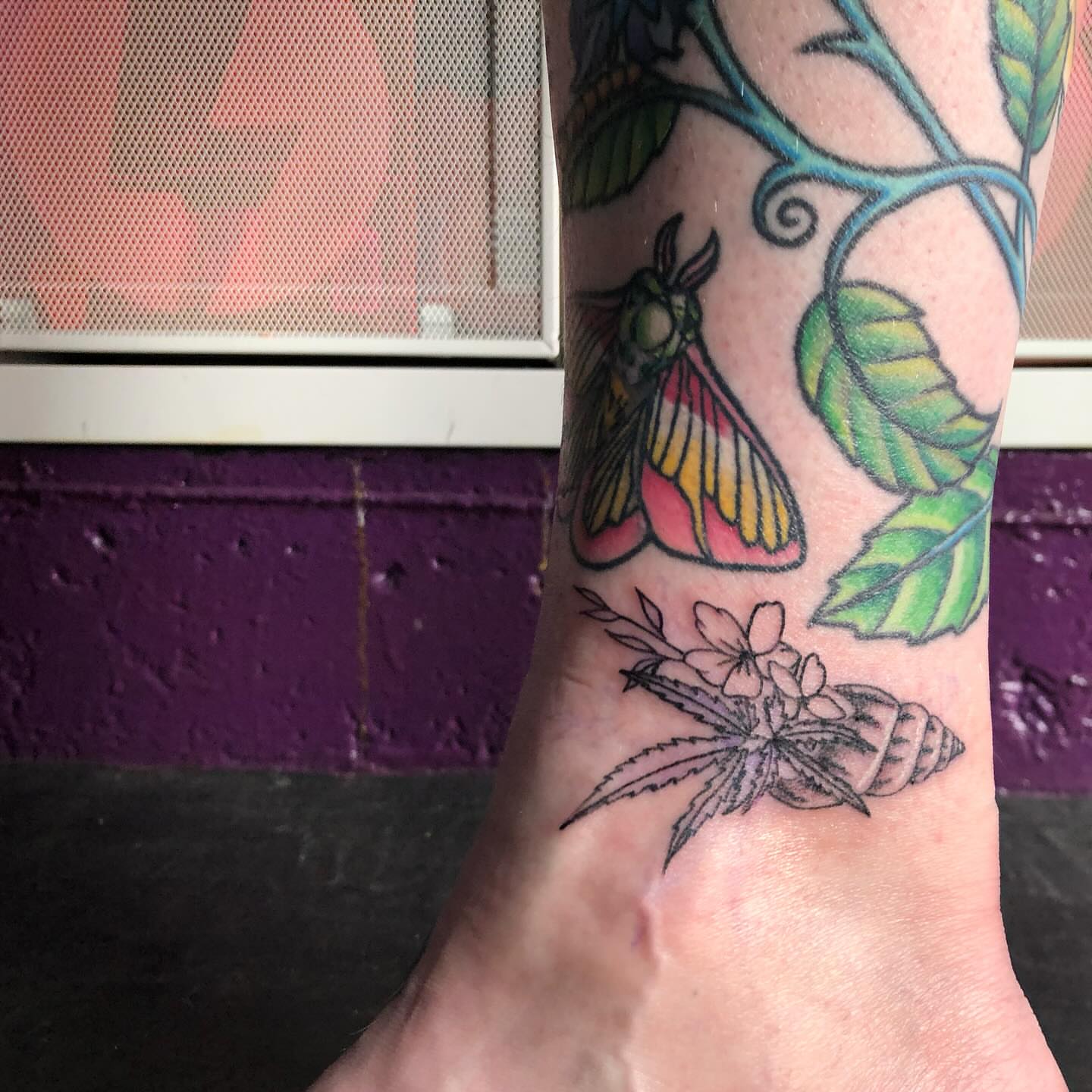Butterfly and cannabis new school tattoo on the forearm by Tesla Kohl