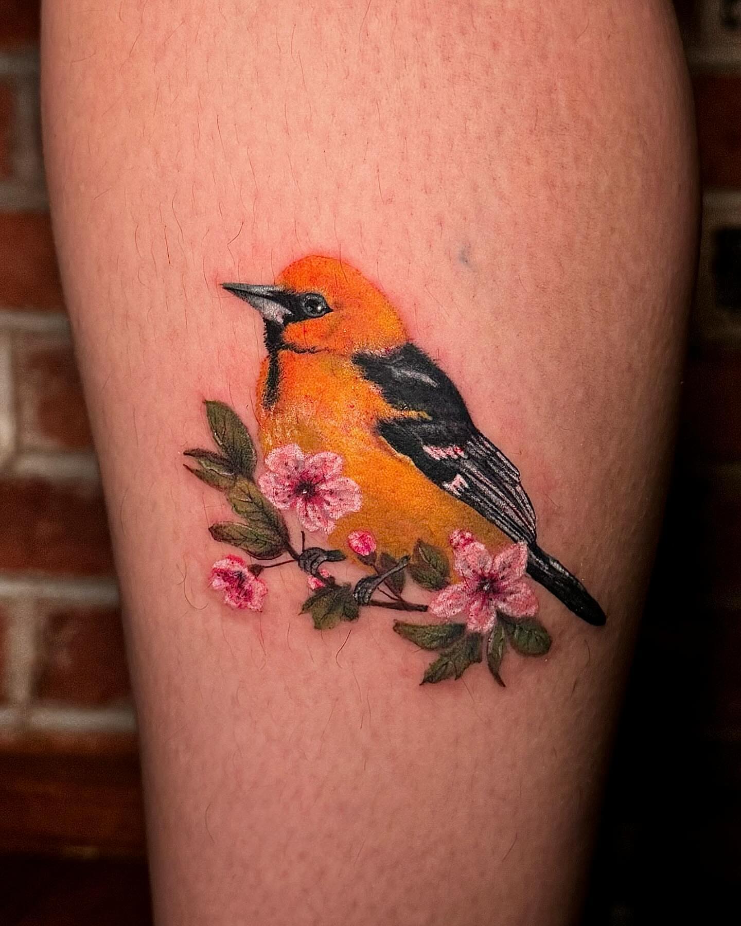 Oriole and blossoms realism tattoo on the thigh by Mishel Castro