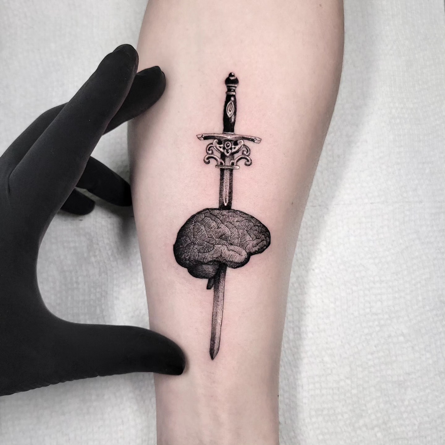 Sword piercing brain realism tattoo on the forearm by miami tattoo artist