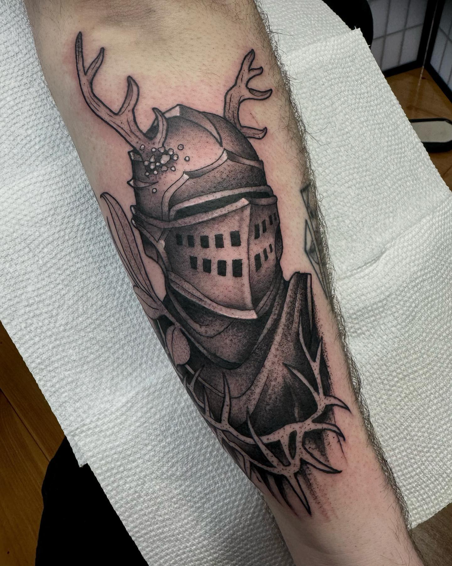 Knight helmet with antlers black and grey tattoo on the forearm by Lauren Peltz