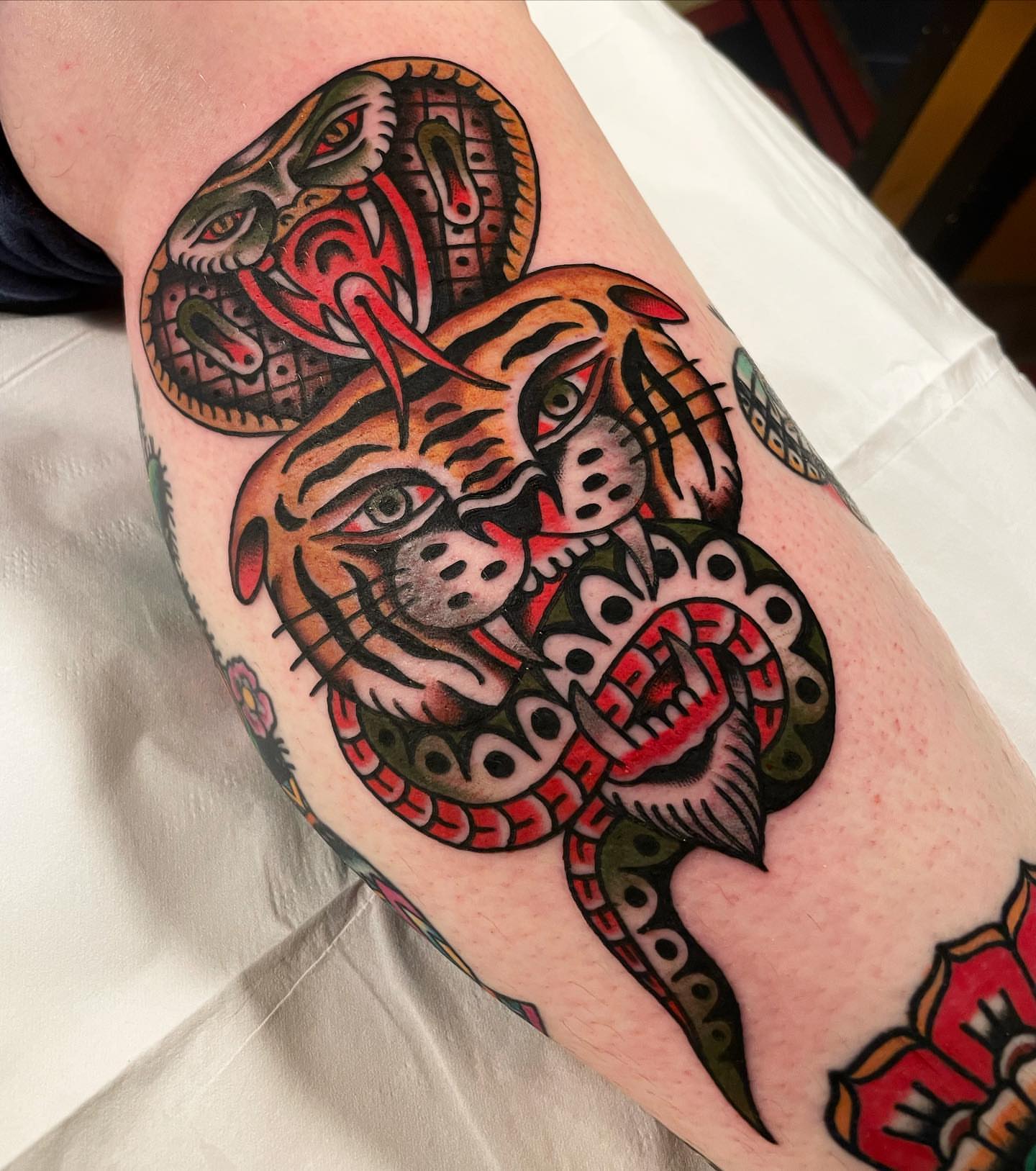 Tiger and snake American traditional tattoo on the forearm by Mike Hudgins