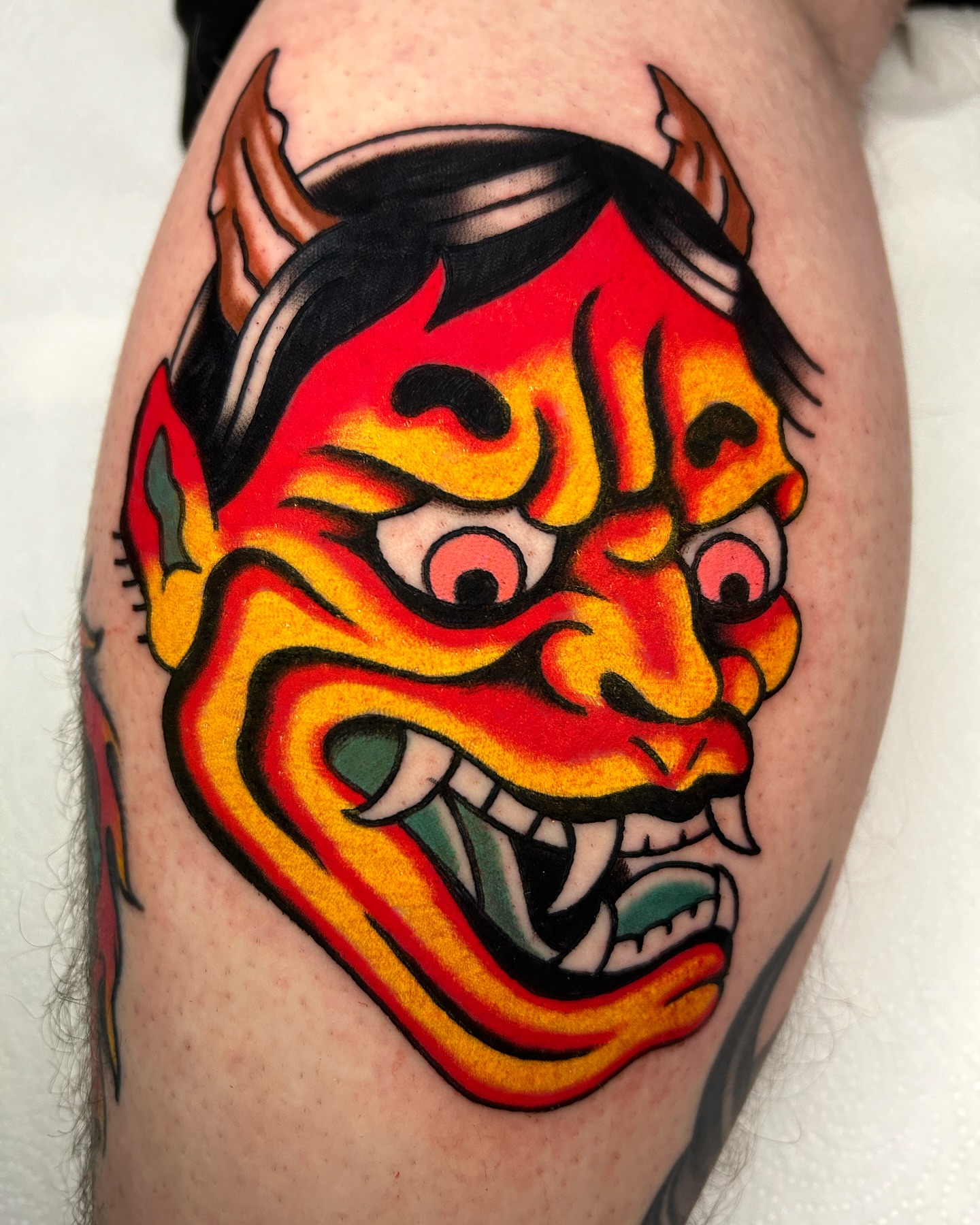 Demon mask American traditional tattoo on the thigh by Mitch Hoggard