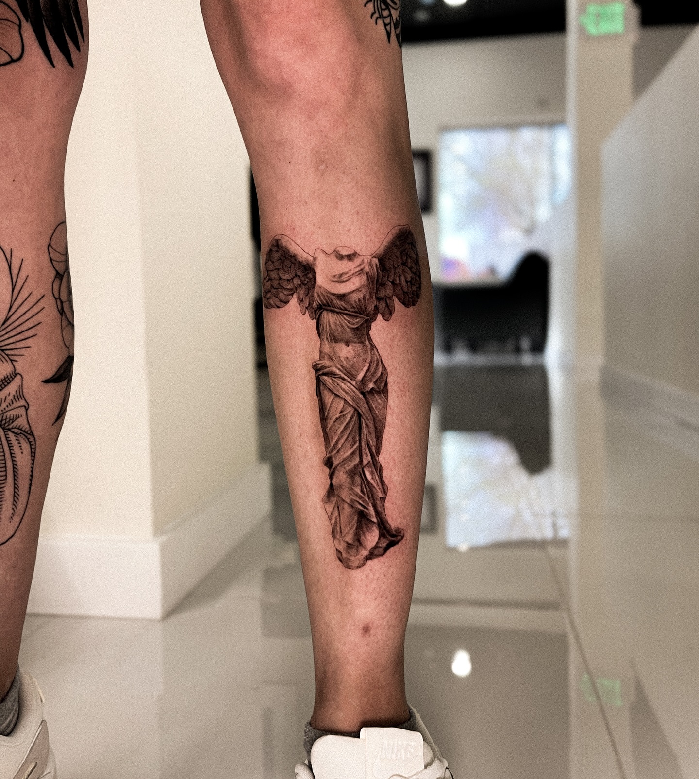 Statue of winged goddess realism tattoo on the calf by Riley K Turner