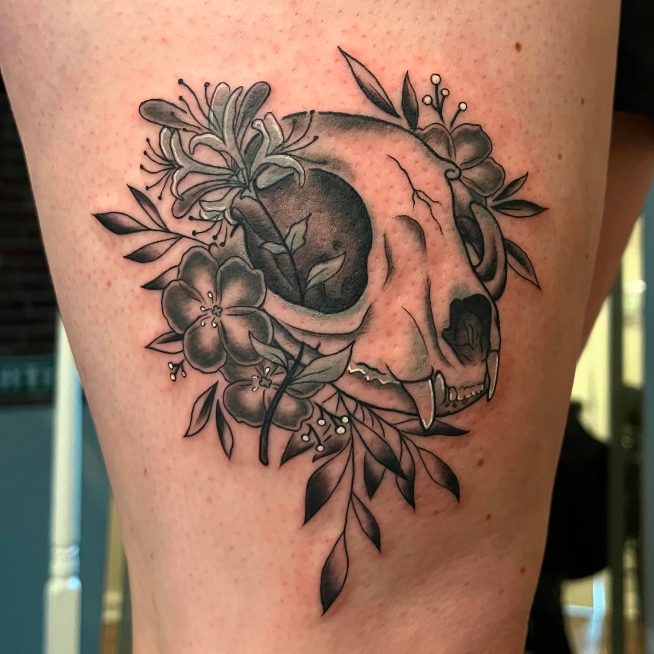 Skull with flowers black and grey tattoo on the thigh by Krystal ✨
