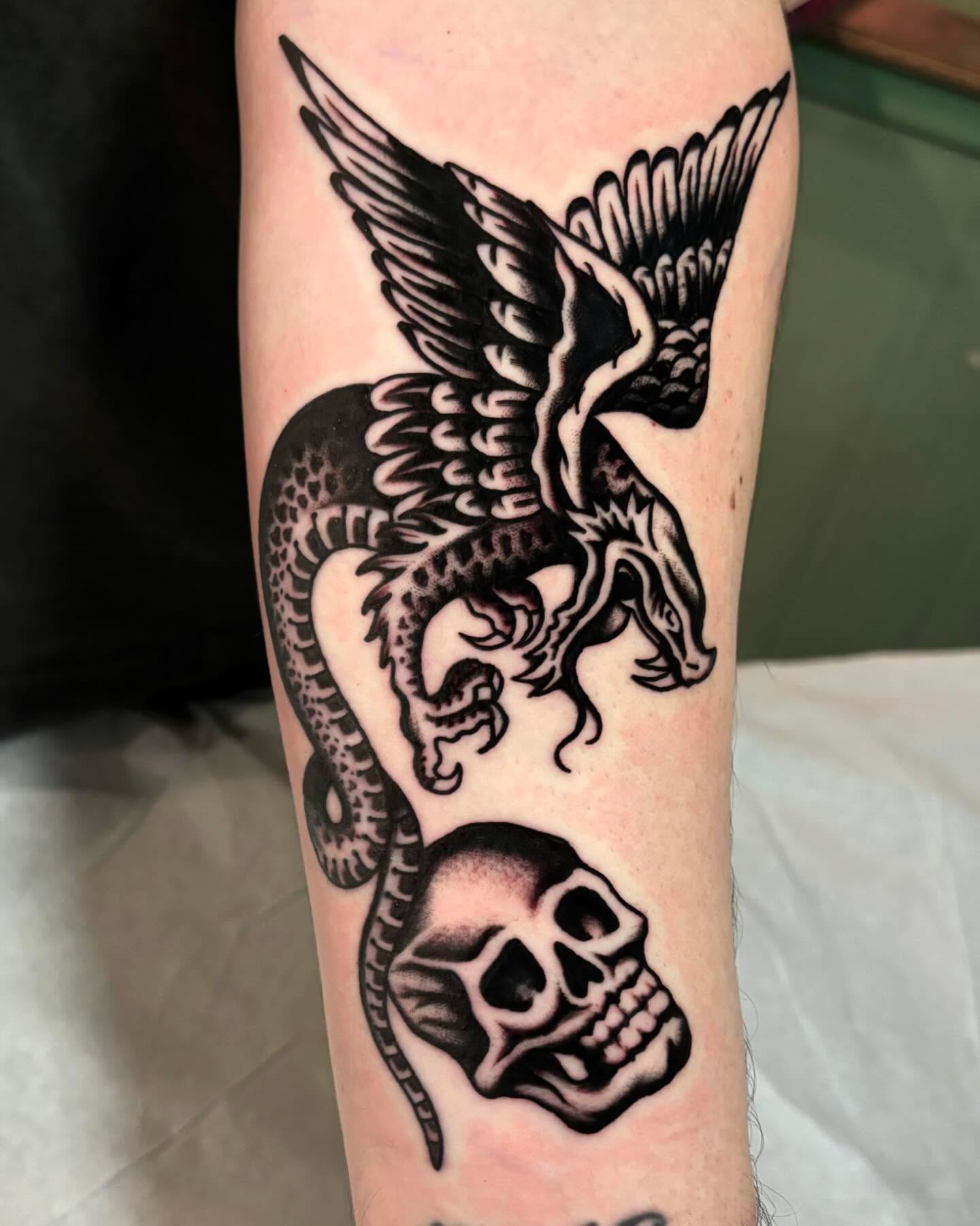 Dragon and skull black and grey tattoo on the forearm by Weston Imhoff