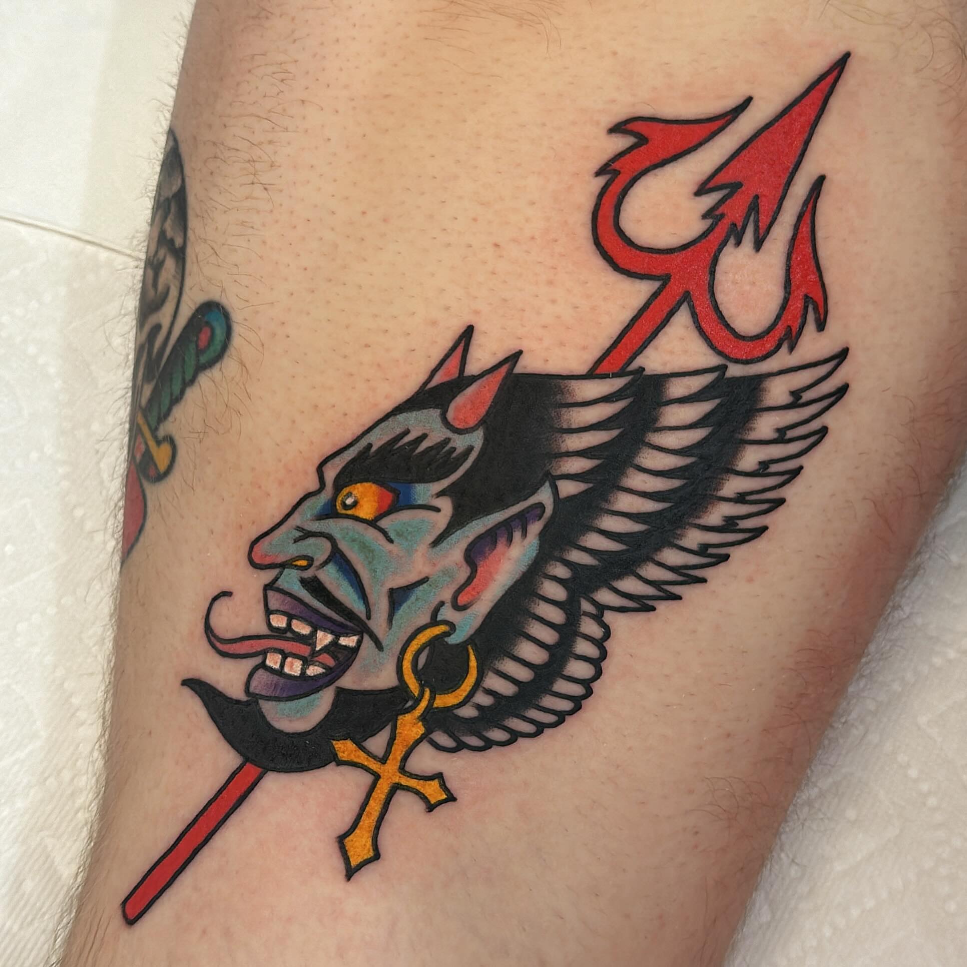 Demon head with trident American traditional tattoo on the thigh by Isaac Brethauer