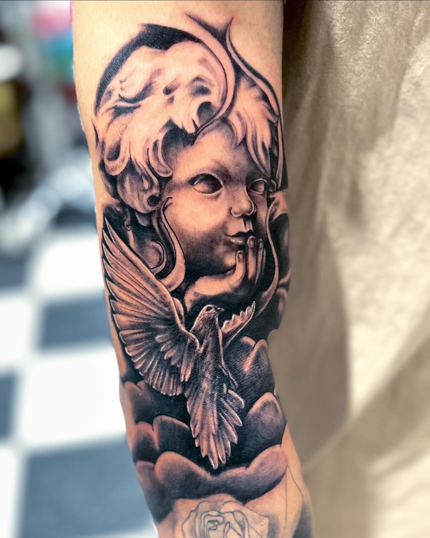 Angelic cherub with bird realism tattoo on the forearm by Morgan Jones