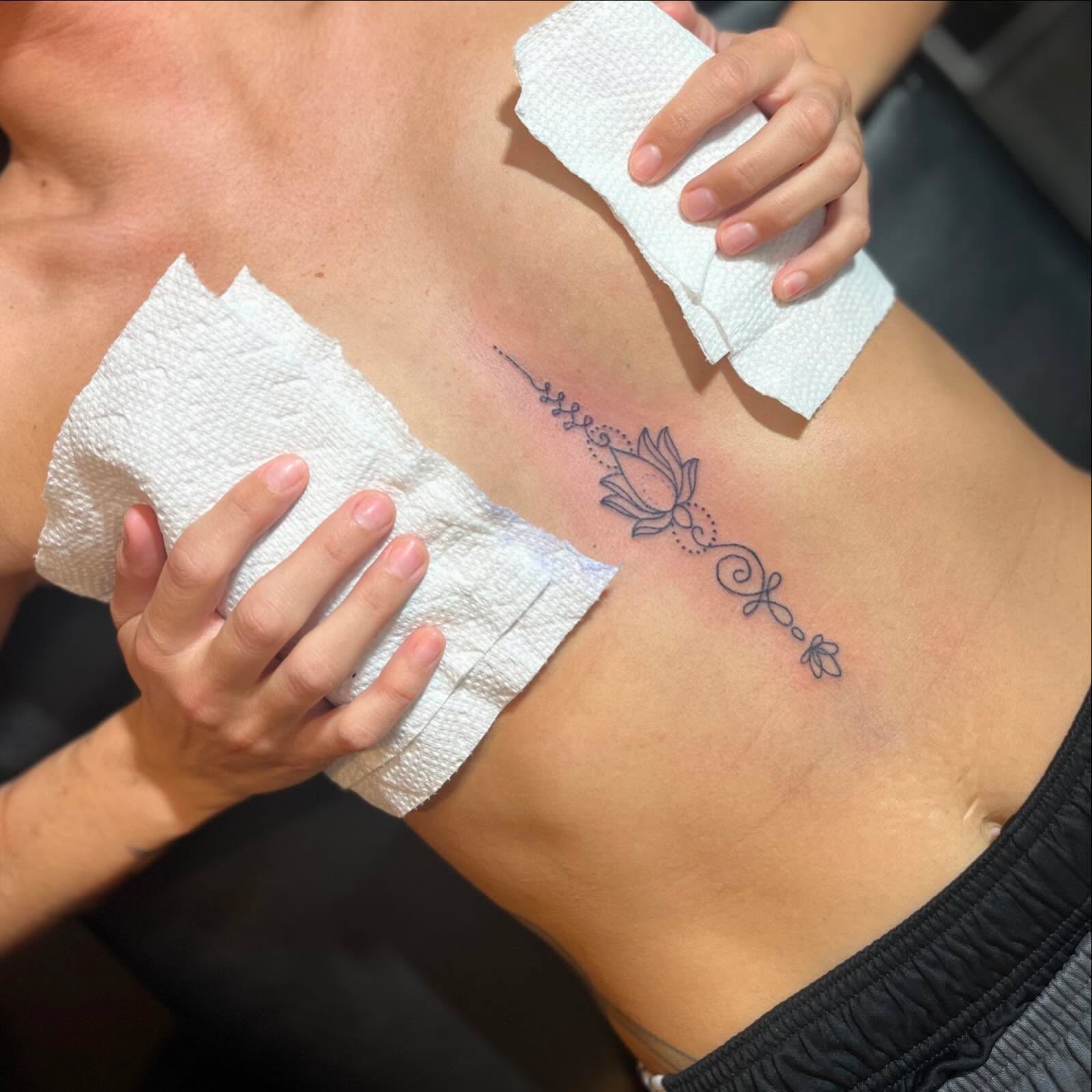 Lotus flower fine line tattoo on the ribs by Alesia