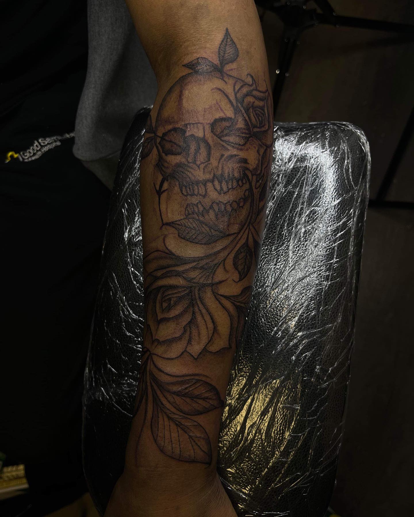 Skull and roses black and grey tattoo on the forearm by Dinero Inks