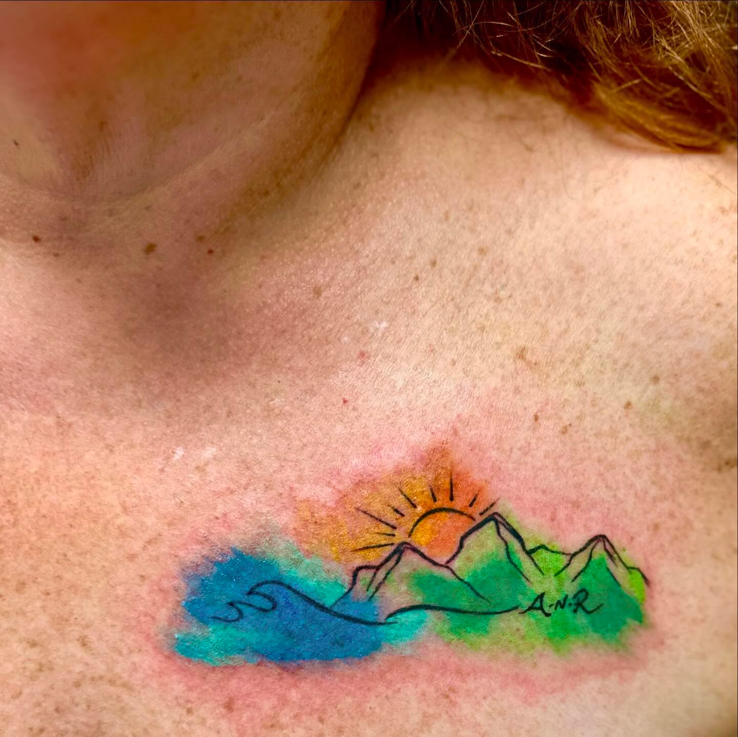 Mountain landscape watercolor tattoo on the chest by Roxanne Ochoa