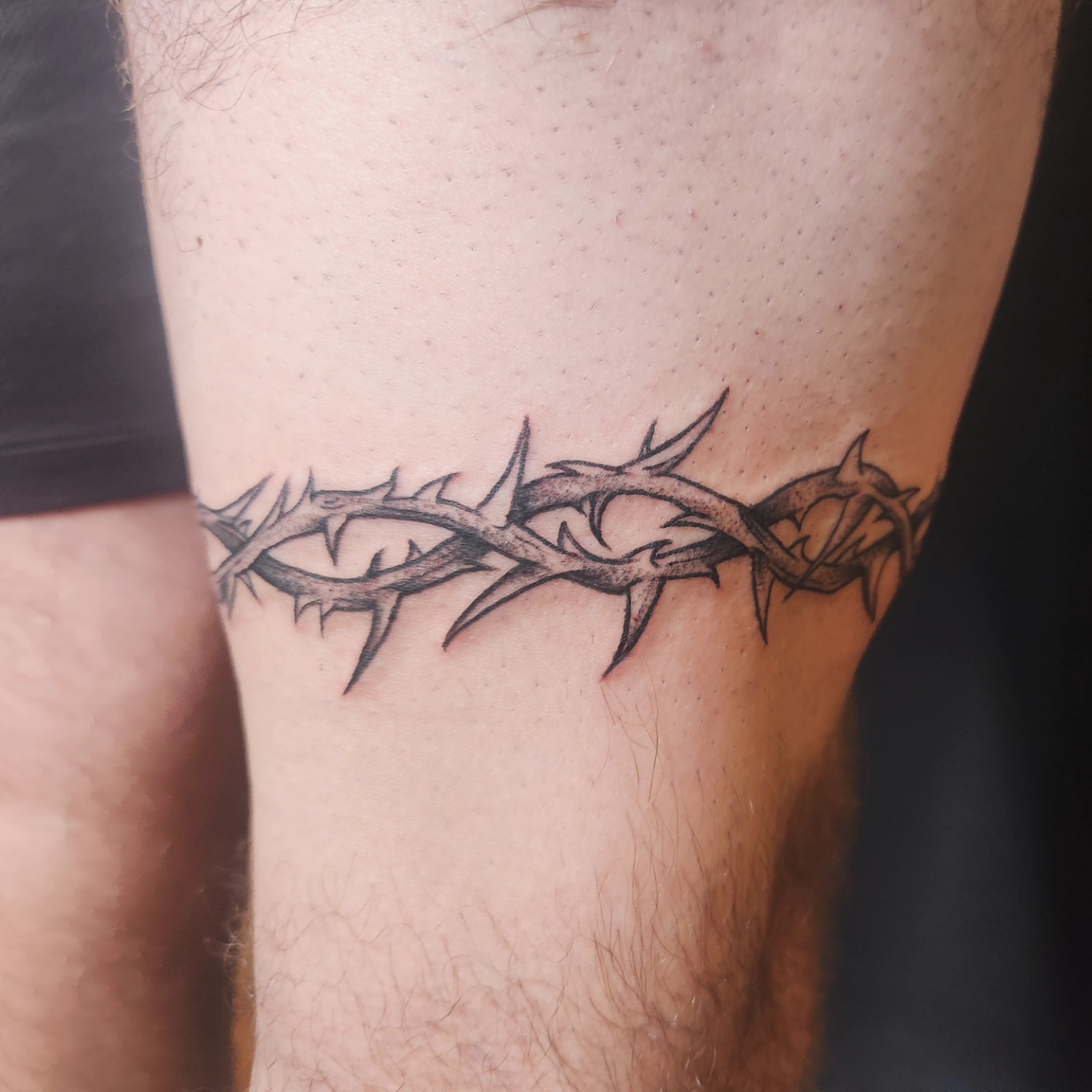 Crown of thorns black and grey tattoo on the thigh by Audrey Luther