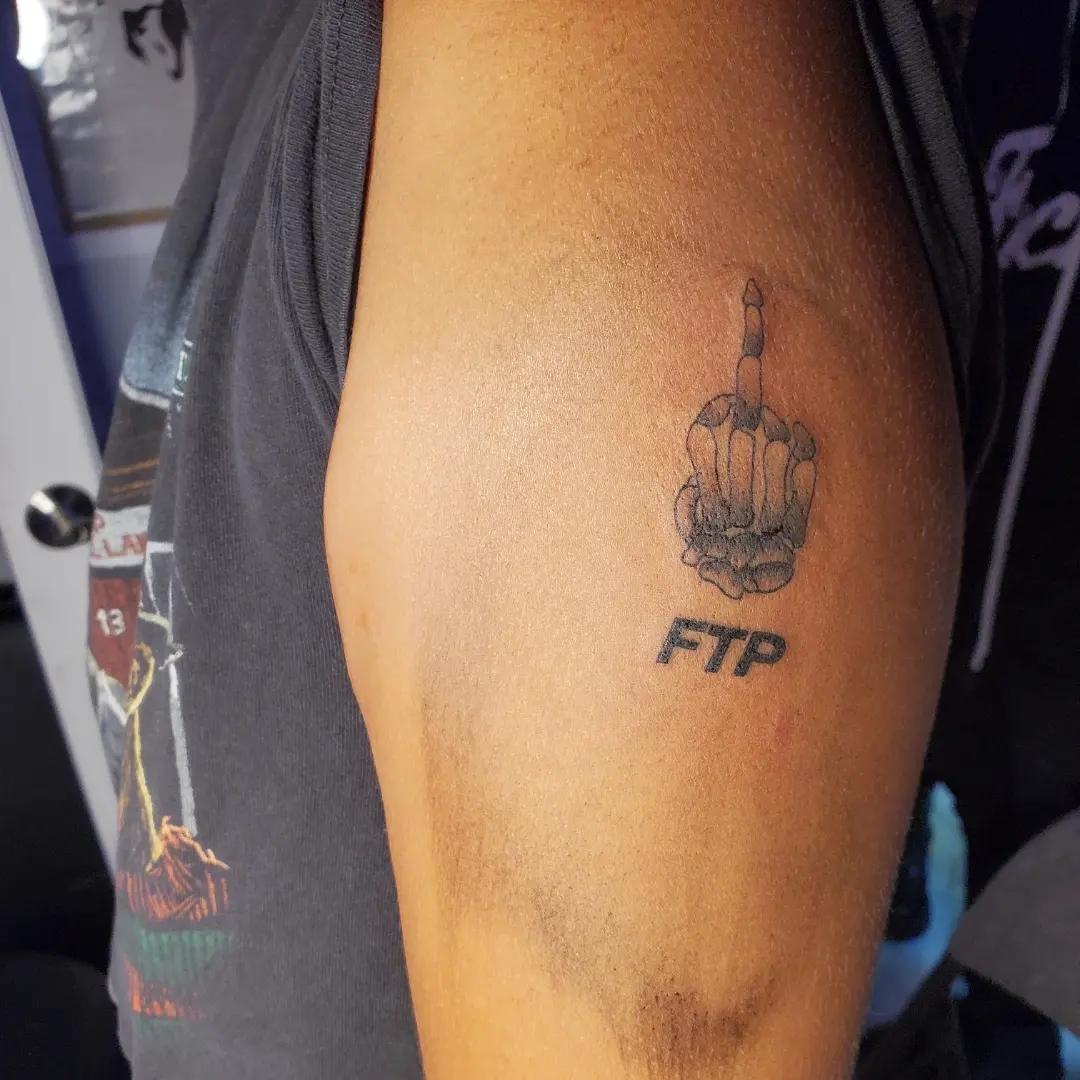 Middle finger gesture black and grey tattoo on the forearm by Joc
