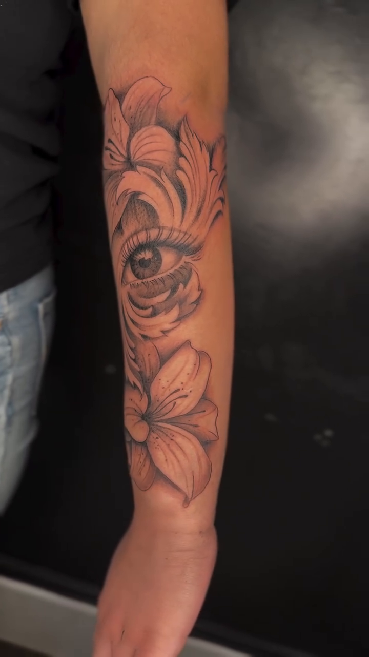 Eye and flowers fine line tattoo on the forearm by Allison Vargas