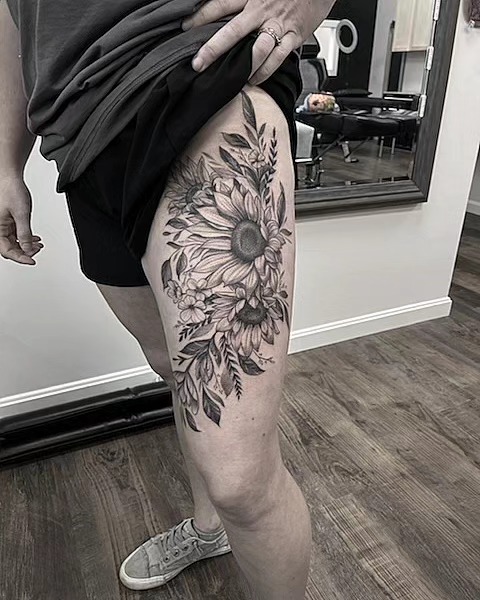 Sunflower and floral arrangement black and grey tattoo on the thigh by Dani Ryan