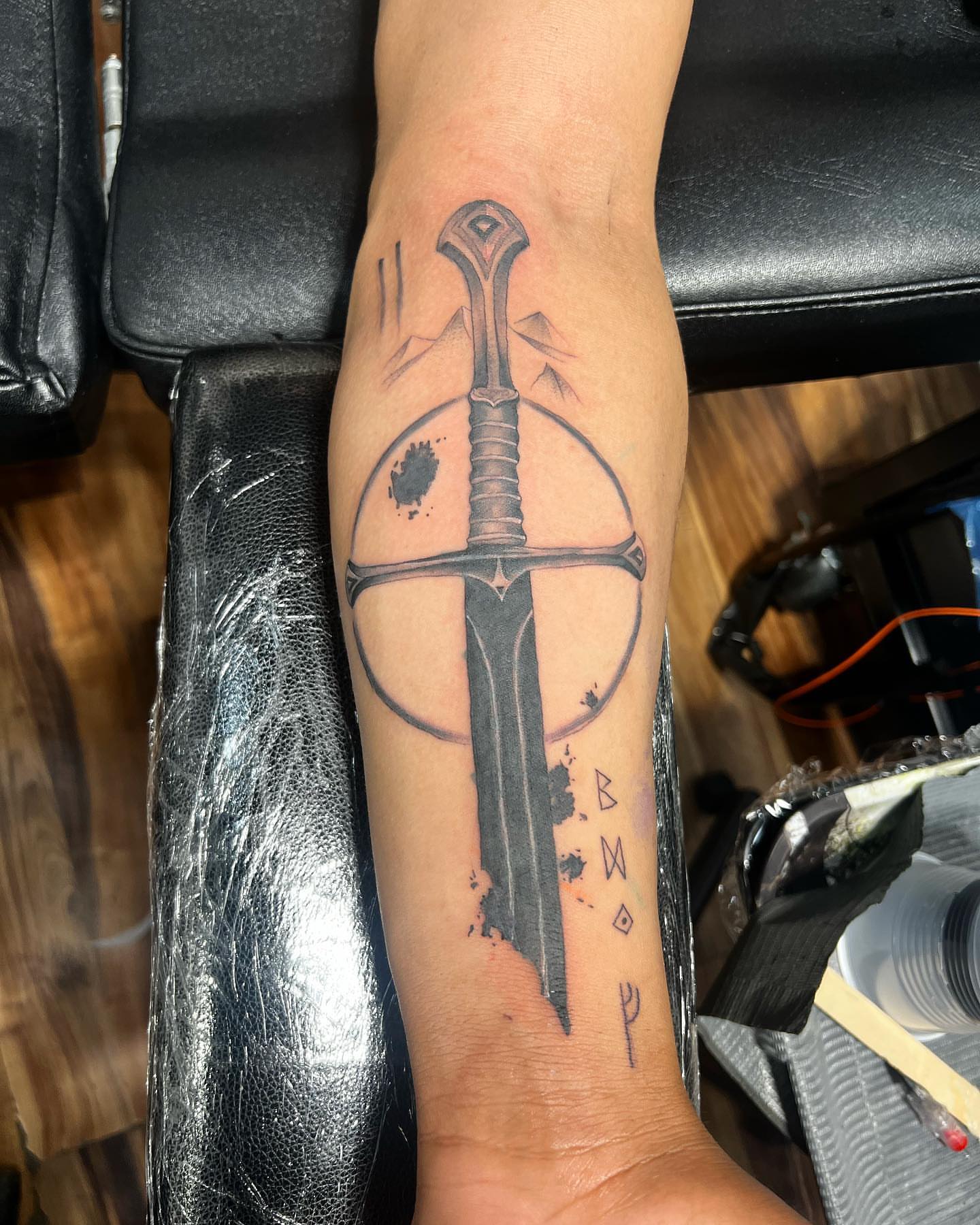 Sword and runes black and grey tattoo on the forearm by Eduardo Chaparro