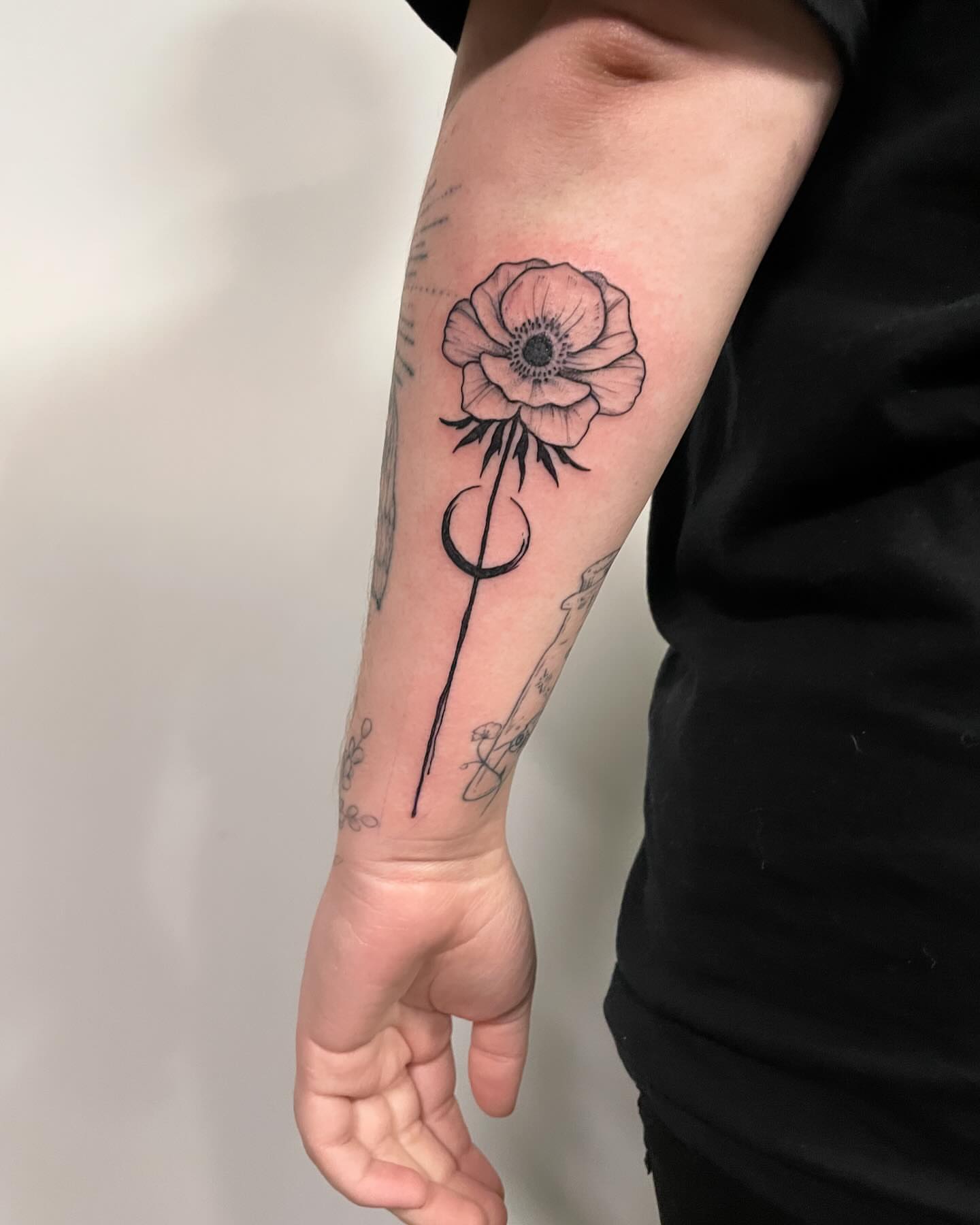 Flower with crescent moon black and grey tattoo on the forearm by Christen Wolfe CA Tattooer