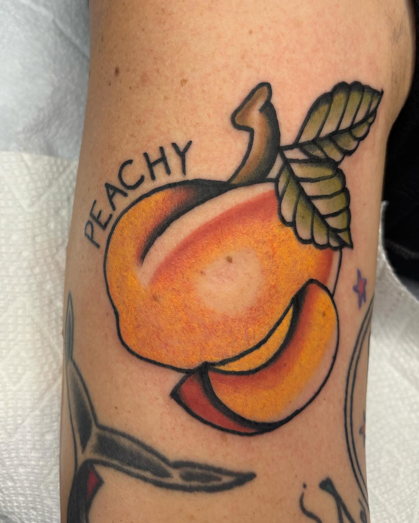 Peach American traditional tattoo on the forearm by Emmy Gallagher