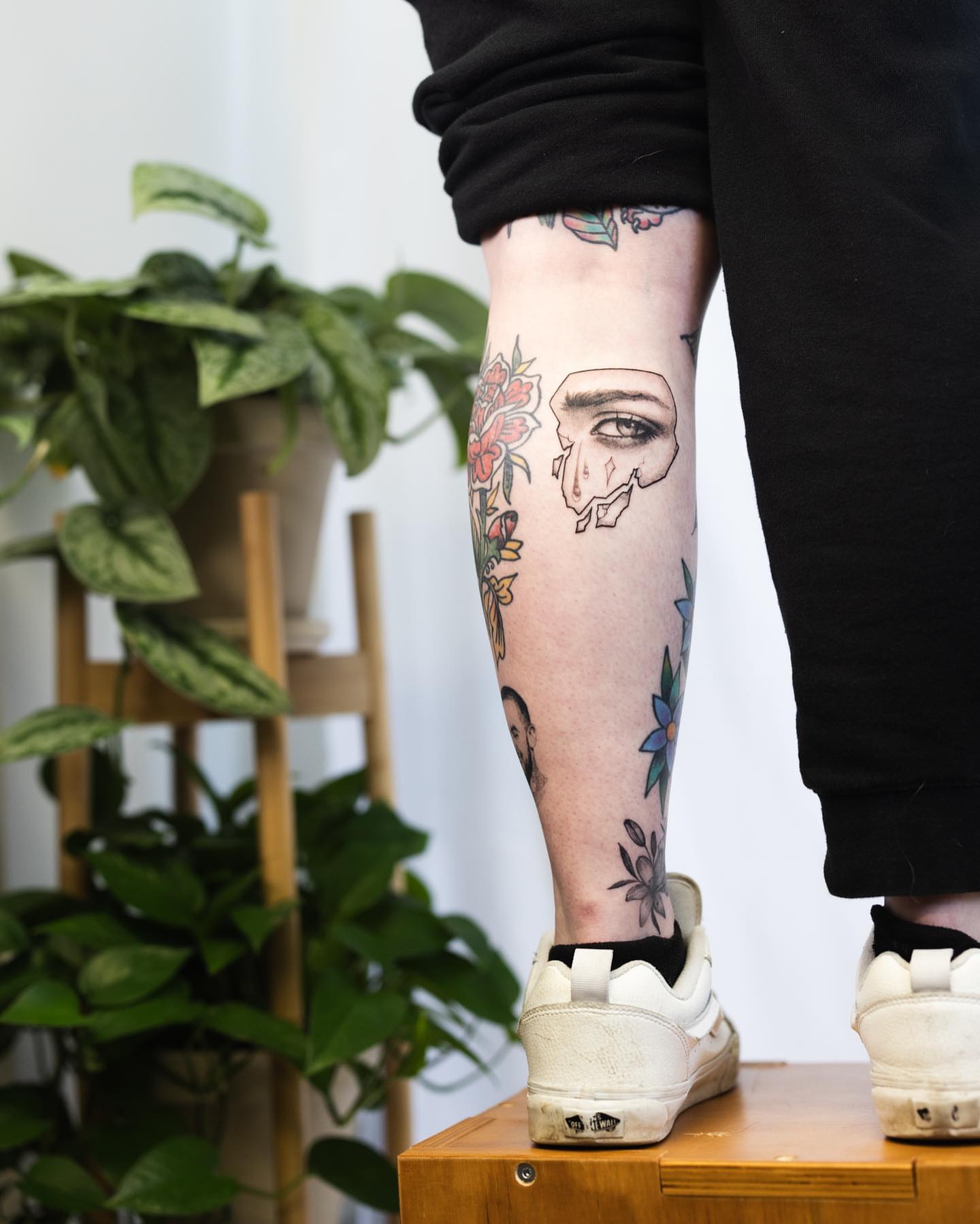 Portrait with floral elements realism tattoo on the calf by Ben Cisek