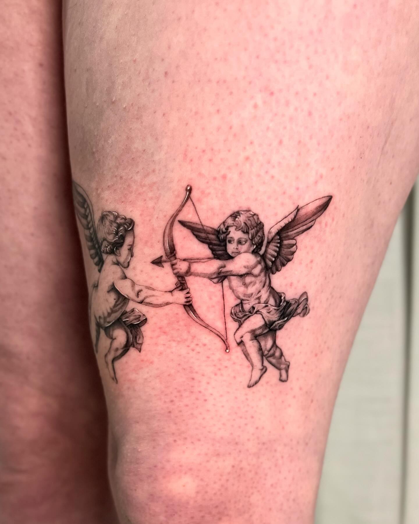 Cherubs black and grey tattoo on the thigh by dom