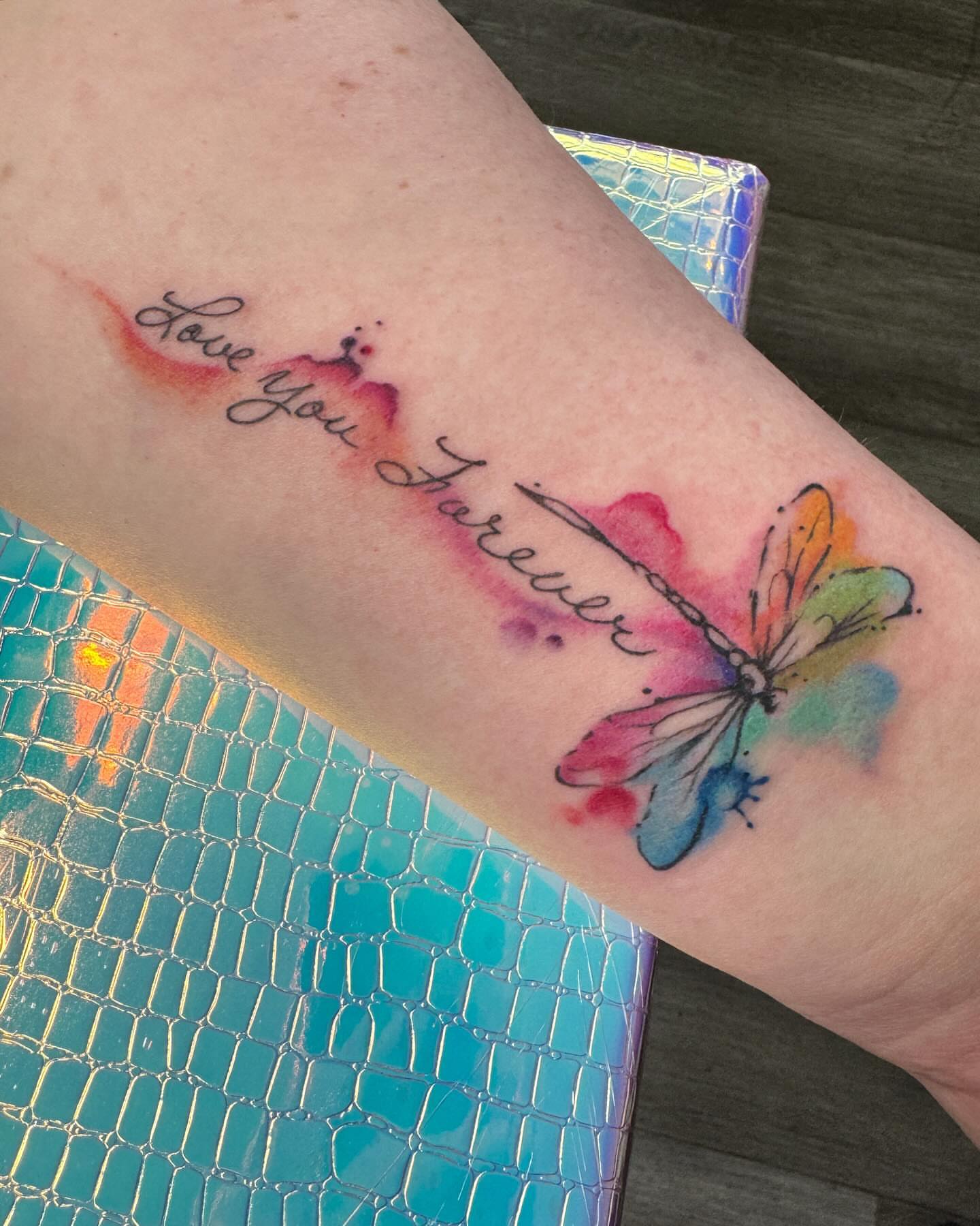 Love you Forever watercolor tattoo on the forearm by Robyn Mahon