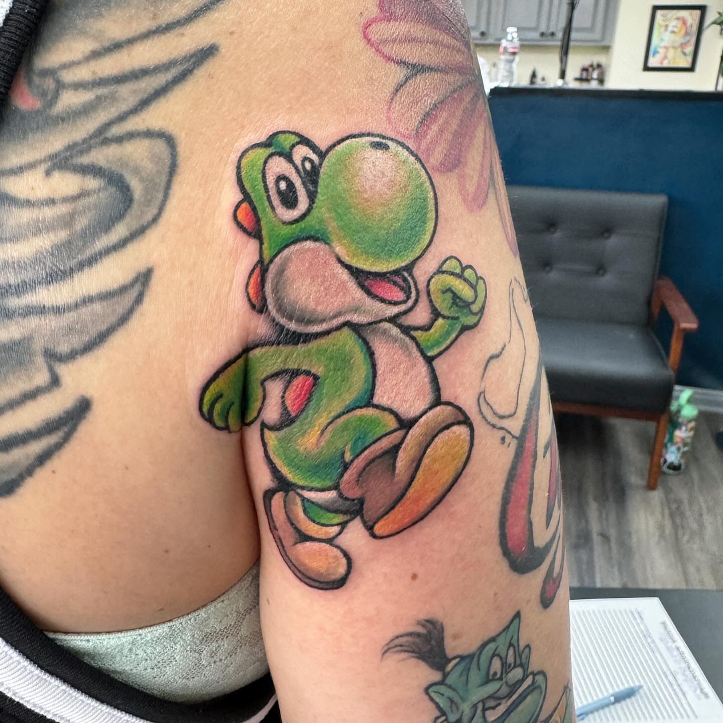 Yoshi new school tattoo on the upper arm by Robyn Mahon