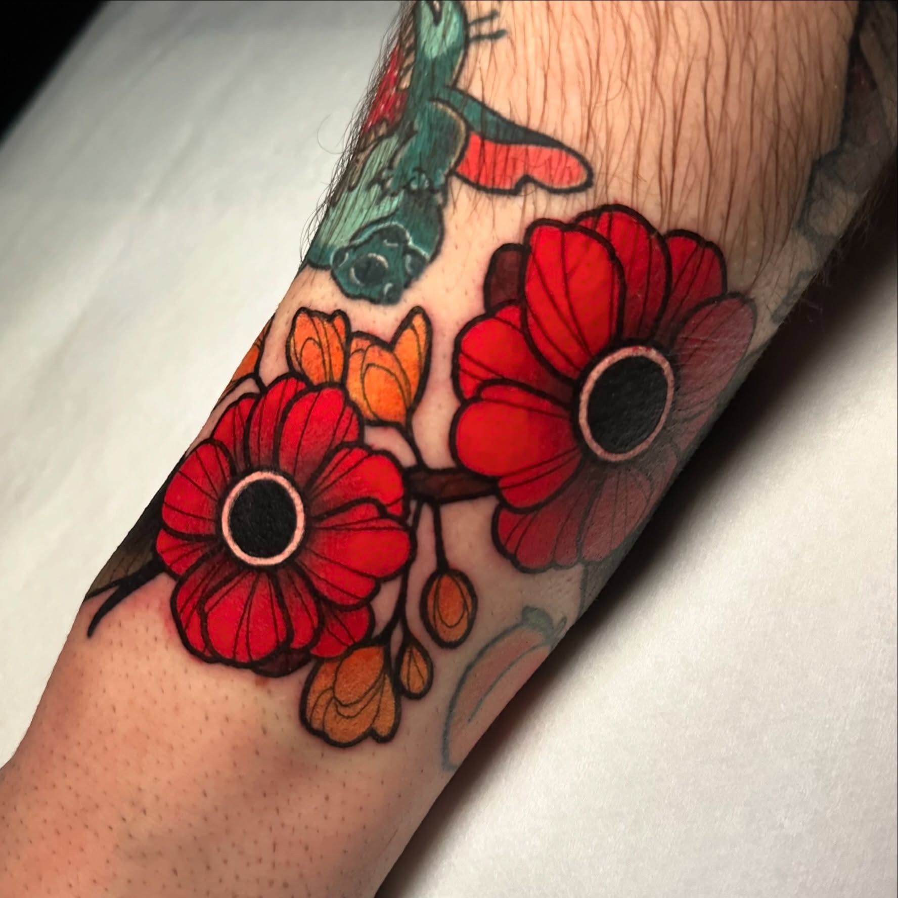 Red poppies American traditional tattoo on the forearm by gillian marie