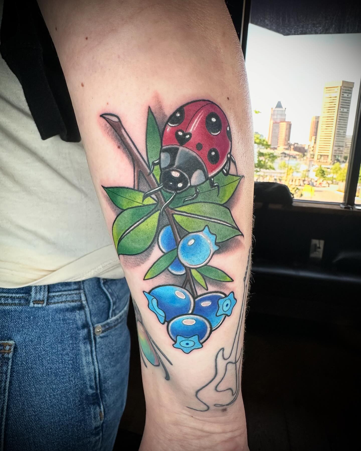 Ladybug and blueberries realism tattoo on the forearm by B.G. Germershausen