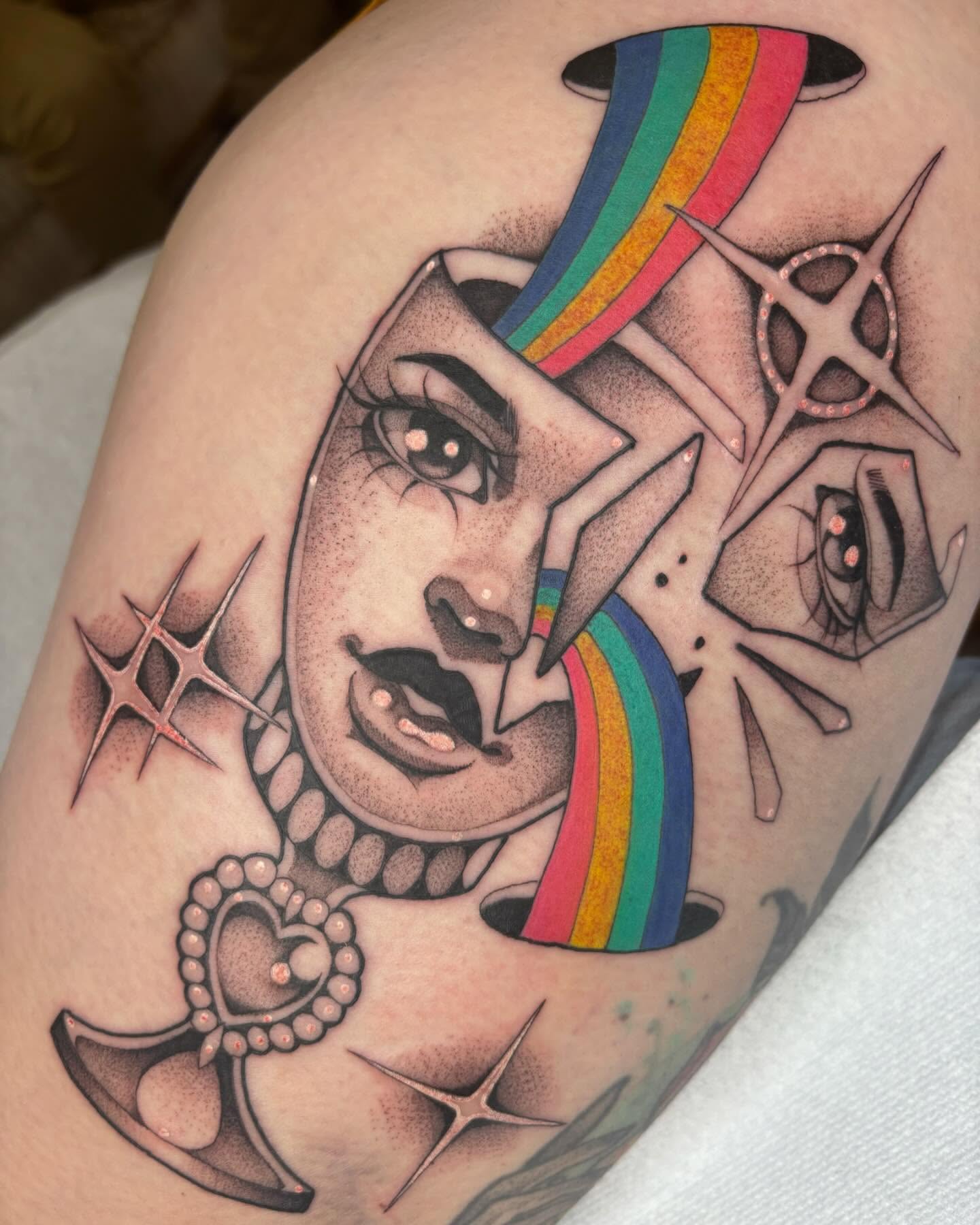 Portrait with rainbow American traditional tattoo on the thigh by Carly Zehring